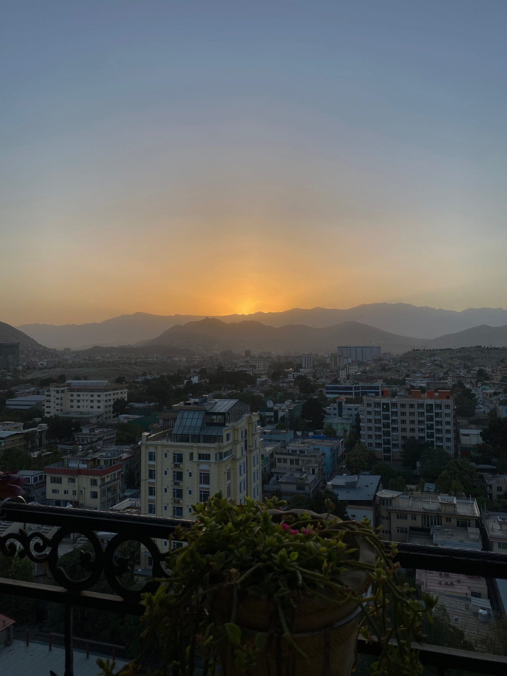 The sun is seen in the distance over the Kabul skyline.
