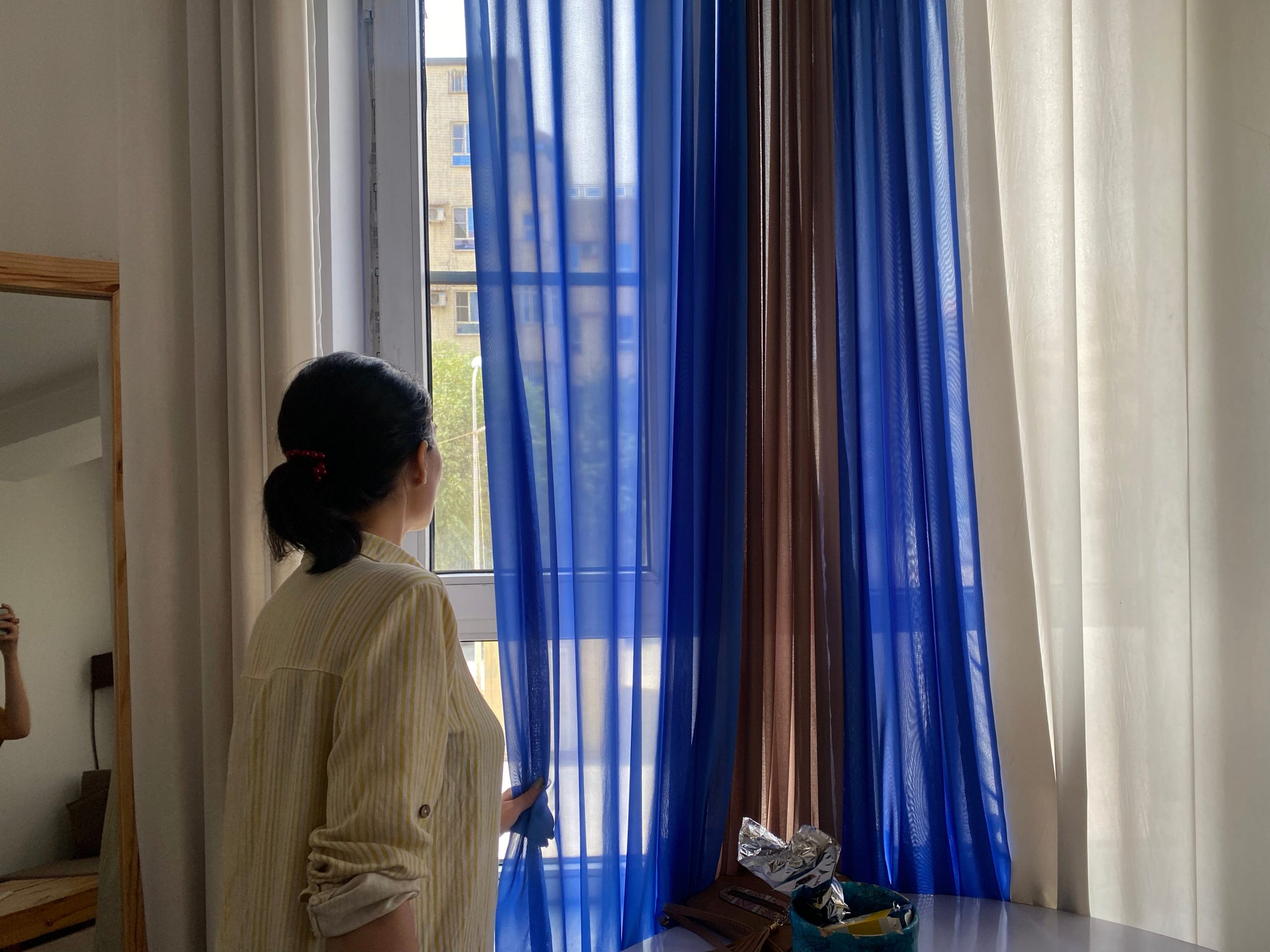 A women looks behind a curtain.