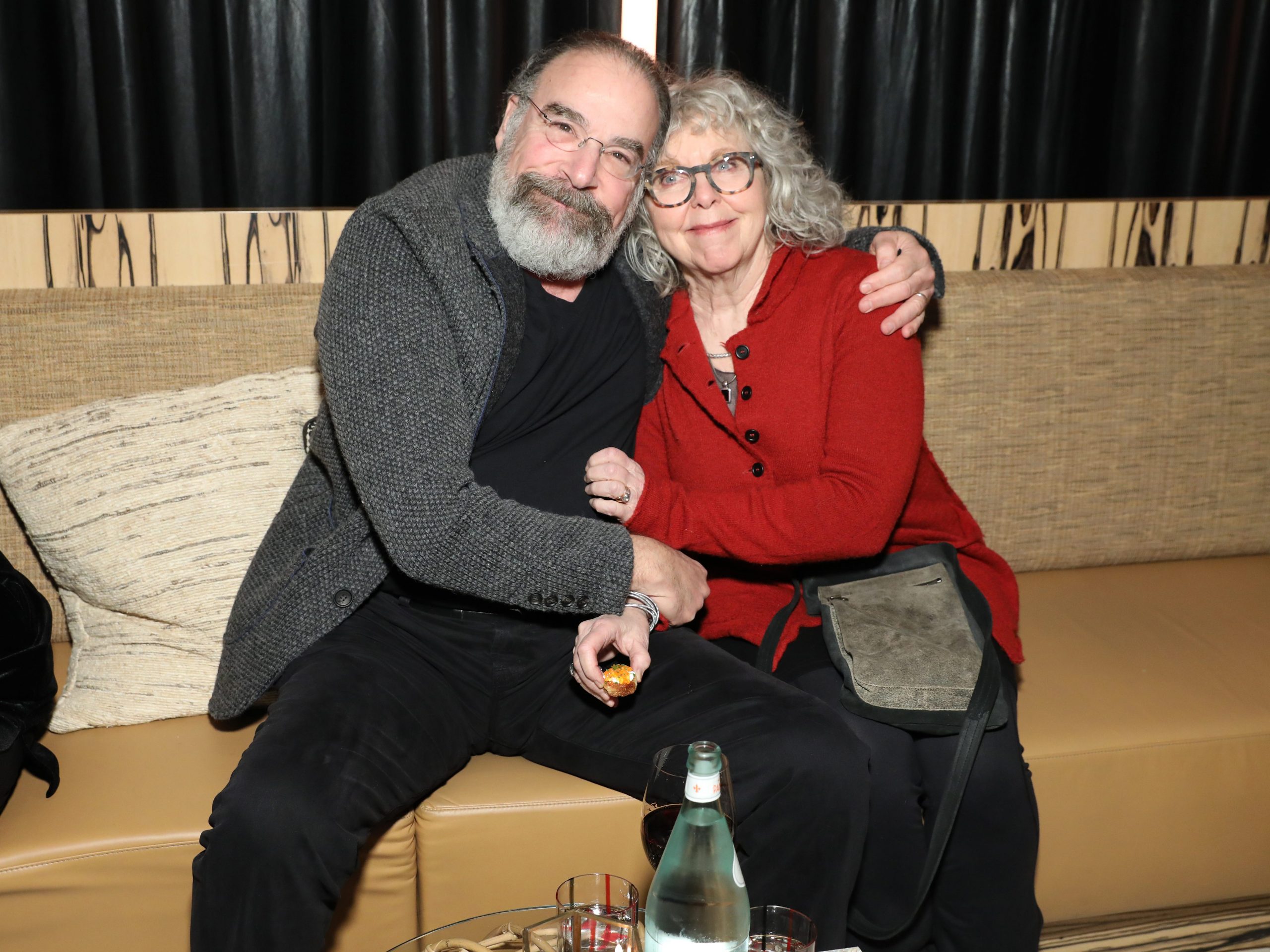 mandy patinkin and his wife kathryn grody embarcing on a couch and smiling