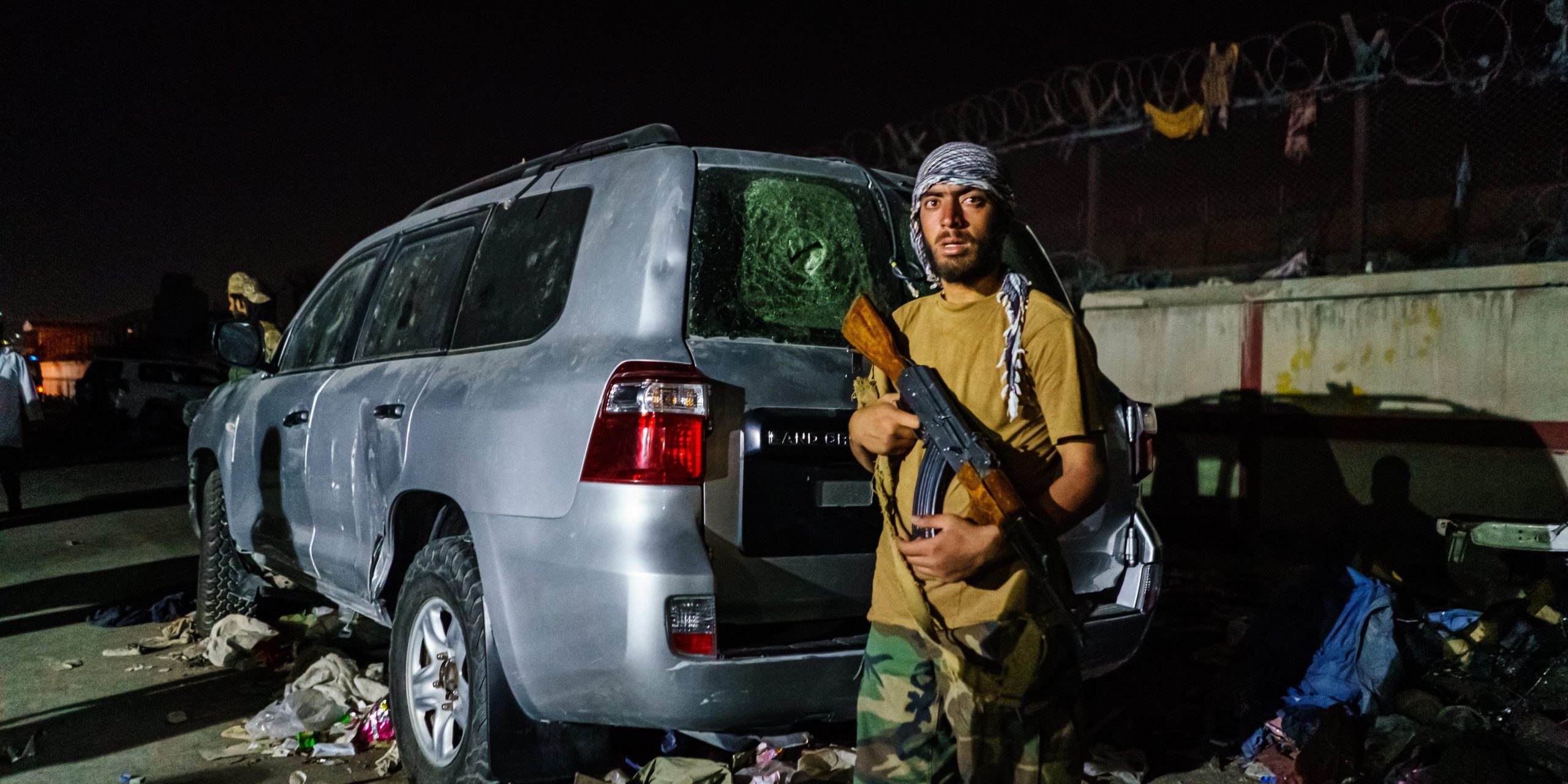 A Taliban fighter stands at an airport checkpoint with a gun.