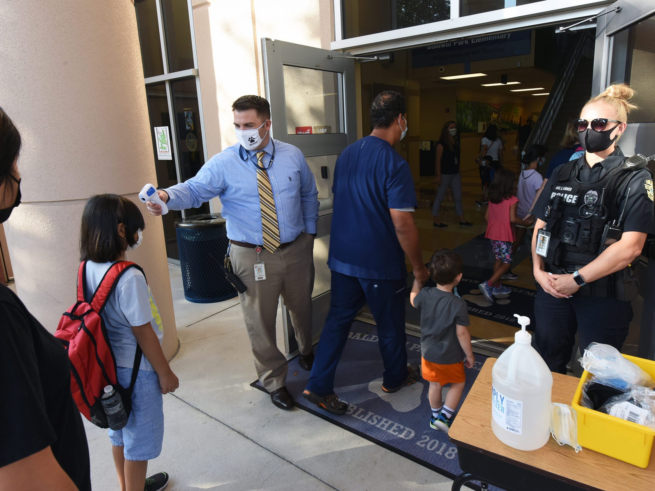 Principal Nathan Hay performs temperature checks on students as they arrive on the first day of classes for the 2021-22 school year at Baldwin Park Elementary School, August 10, 2021.