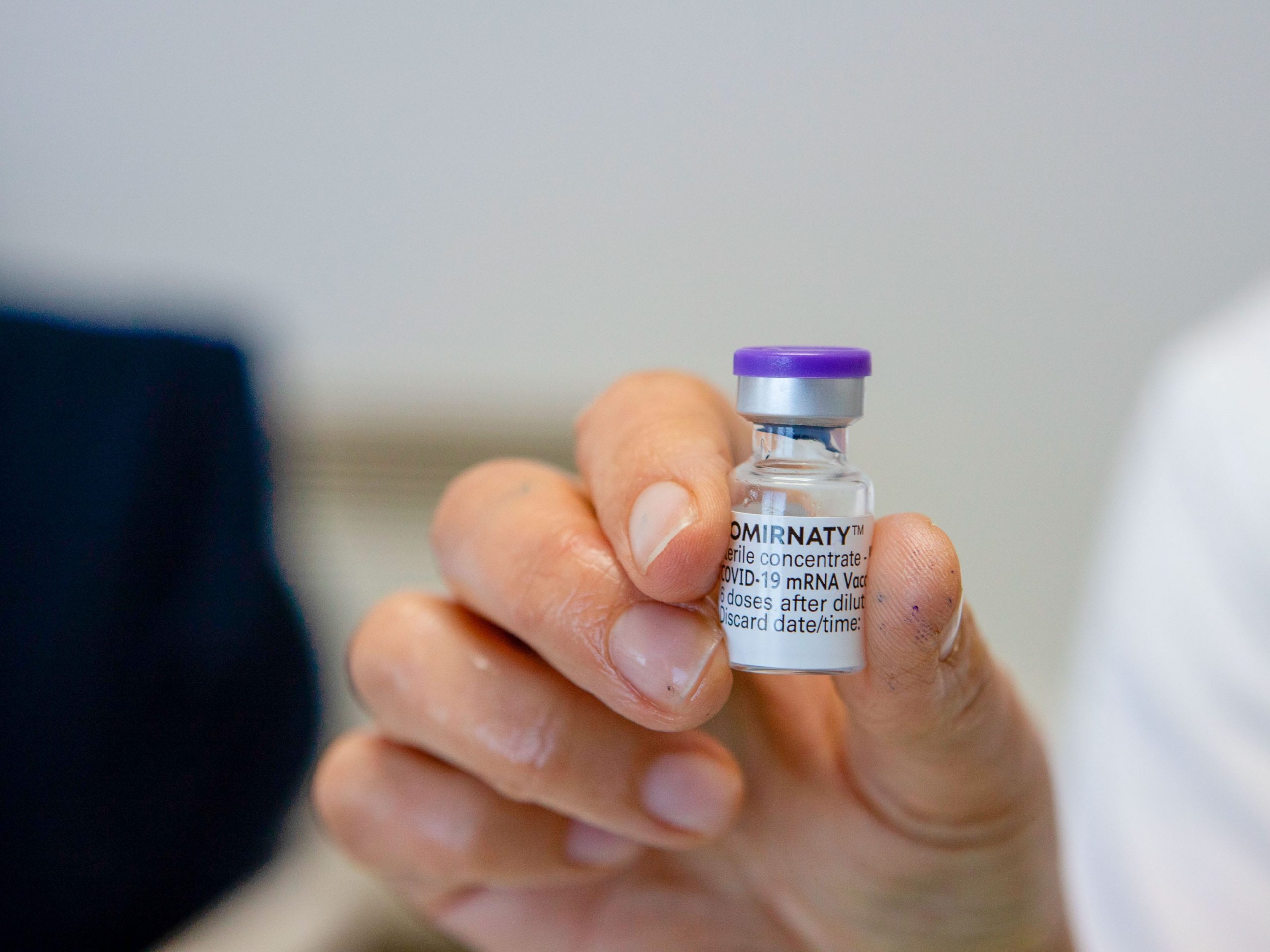 A health worker seen holding a vial containing the Cominarty vaccine.