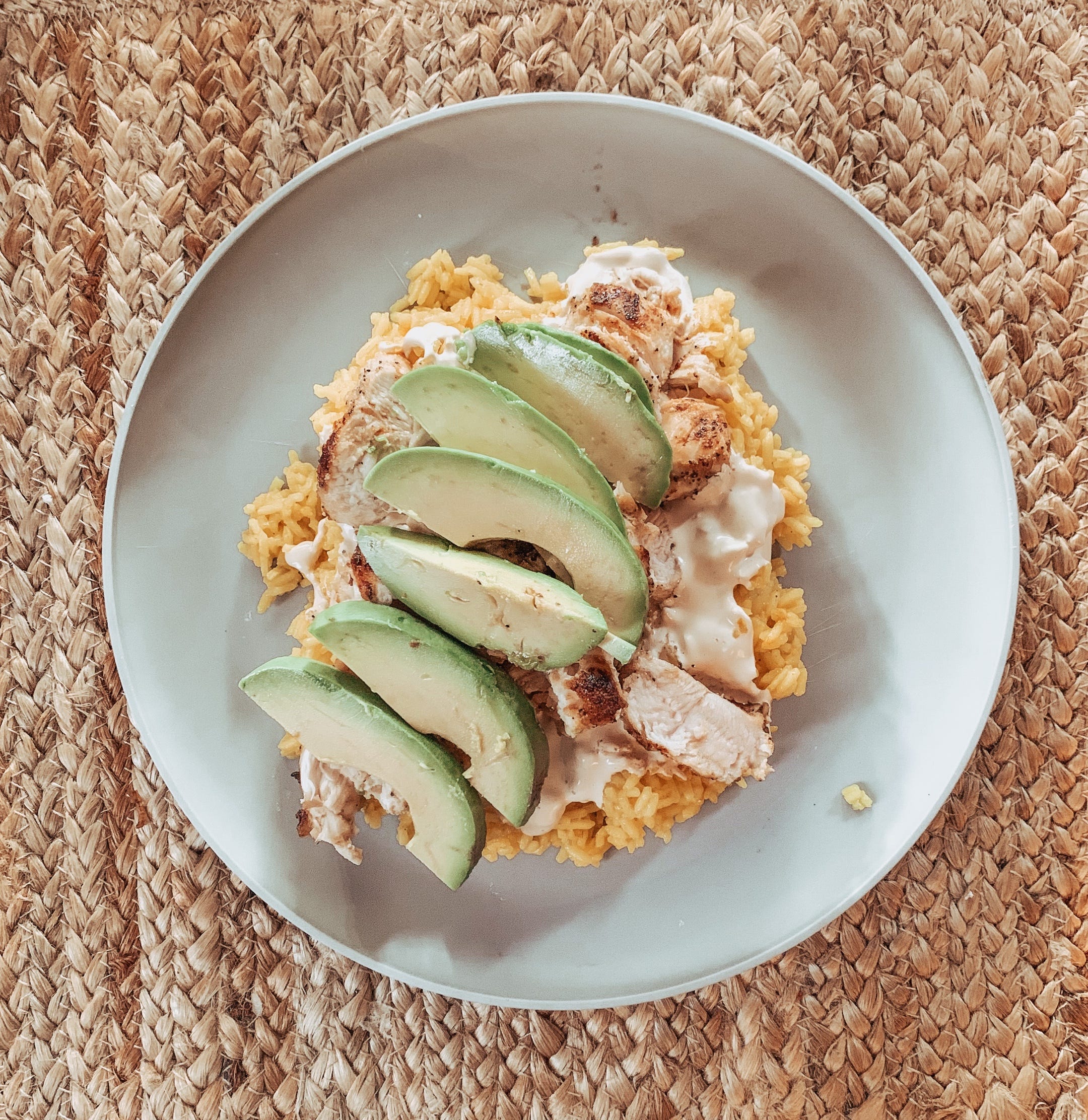 A plate of rice, chicken, and avocado.