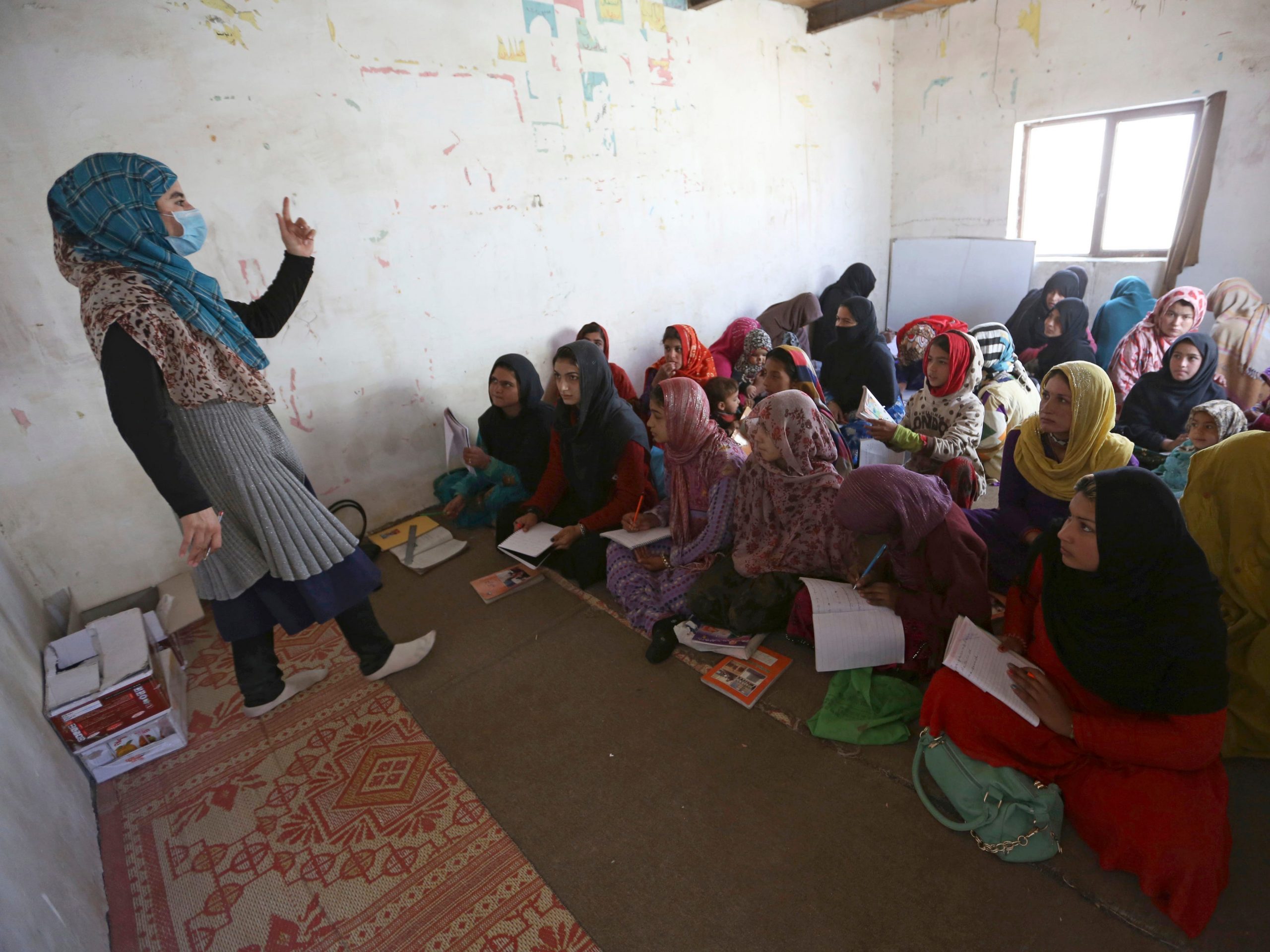 In this Oct. 30, 2017, file photo, Afghan internally displaced school girls and women study at a class near their temporary homes on the outskirts of Kabul. Attacks on schools in Afghanistan tripled in 2018, compared to the year before, in part because militants targeted schools that were used as polling stations in the country's October parliamentary elections, the United Nations children's agency said Tuesday, May 28, 2019.