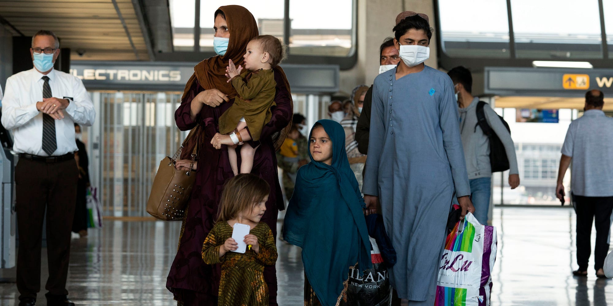 Families evacuated from Kabul, Afghanistan, walk through the terminal before boarding a bus after they arrived at Washington Dulles International Airport, in Chantilly, Va., on Friday, Aug. 27, 2021.