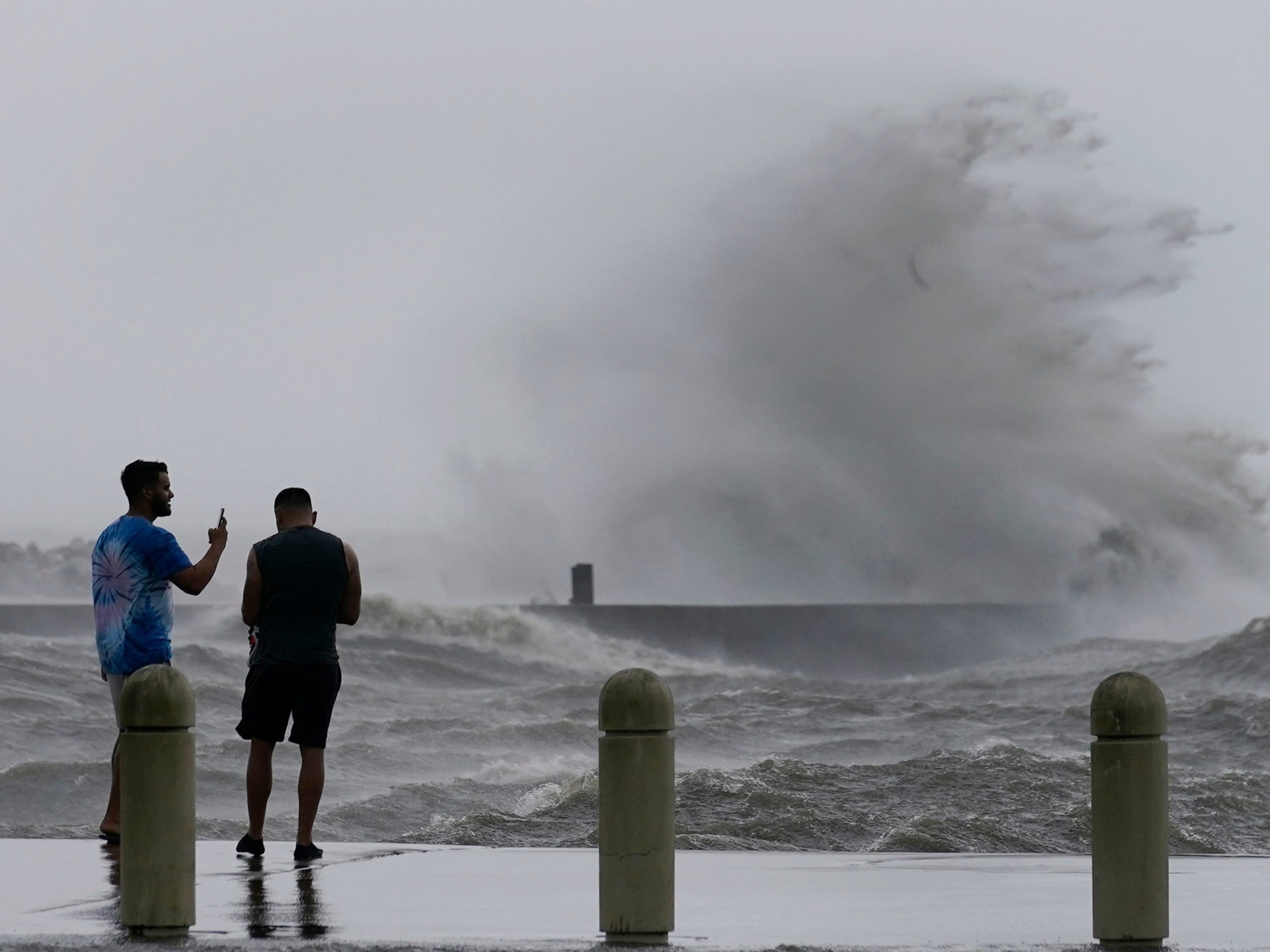 Two men stand in front of high waves on Lake Pontchartrain as Hurricane Ida nears, Sunday, Aug. 29, 2021, in New Orleans.