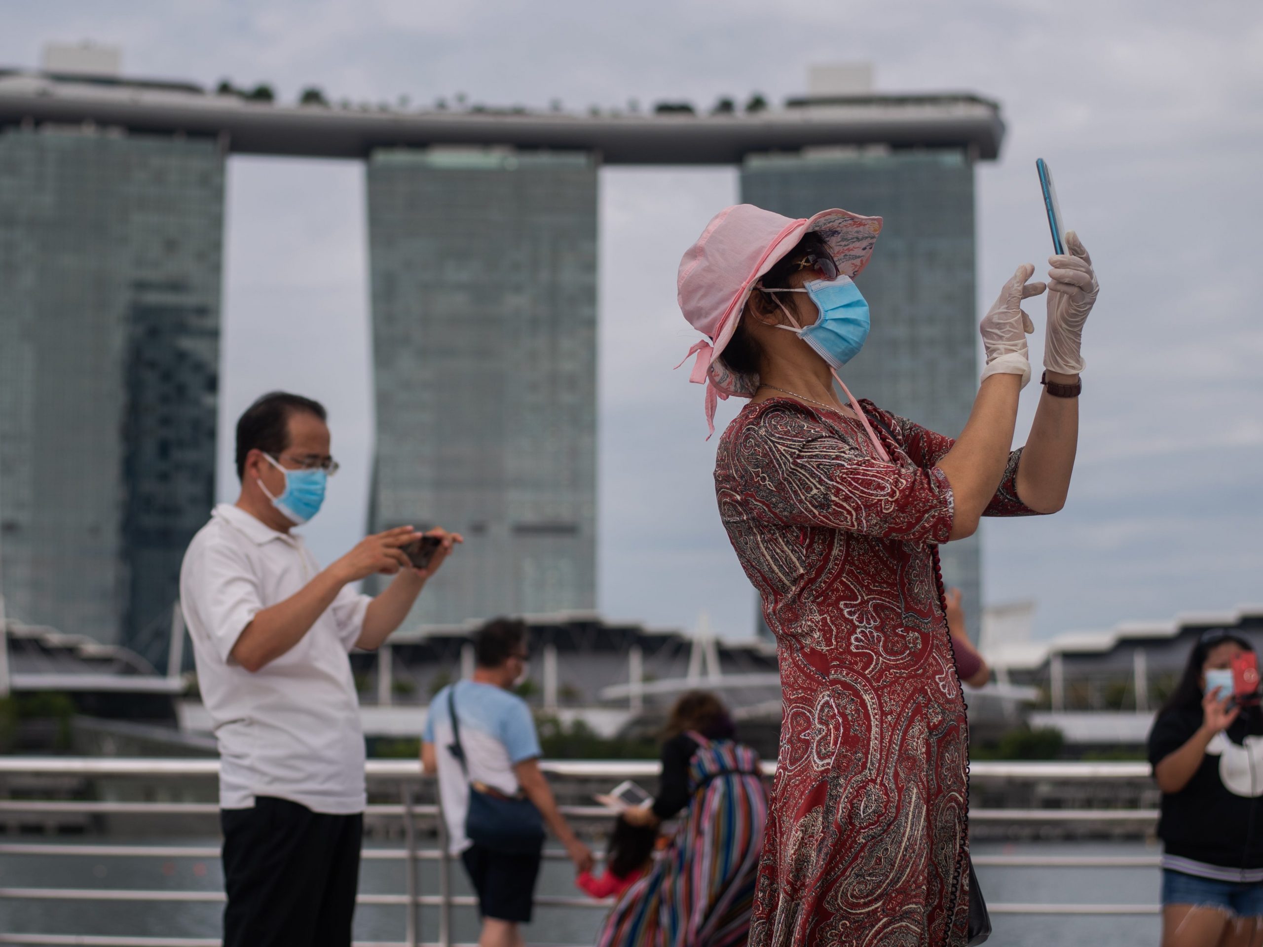 A woman wearing 2 masks and gloves takes pictures at Singapore's Marina Bay on Sunday, August 01, 2021 in Singapore.