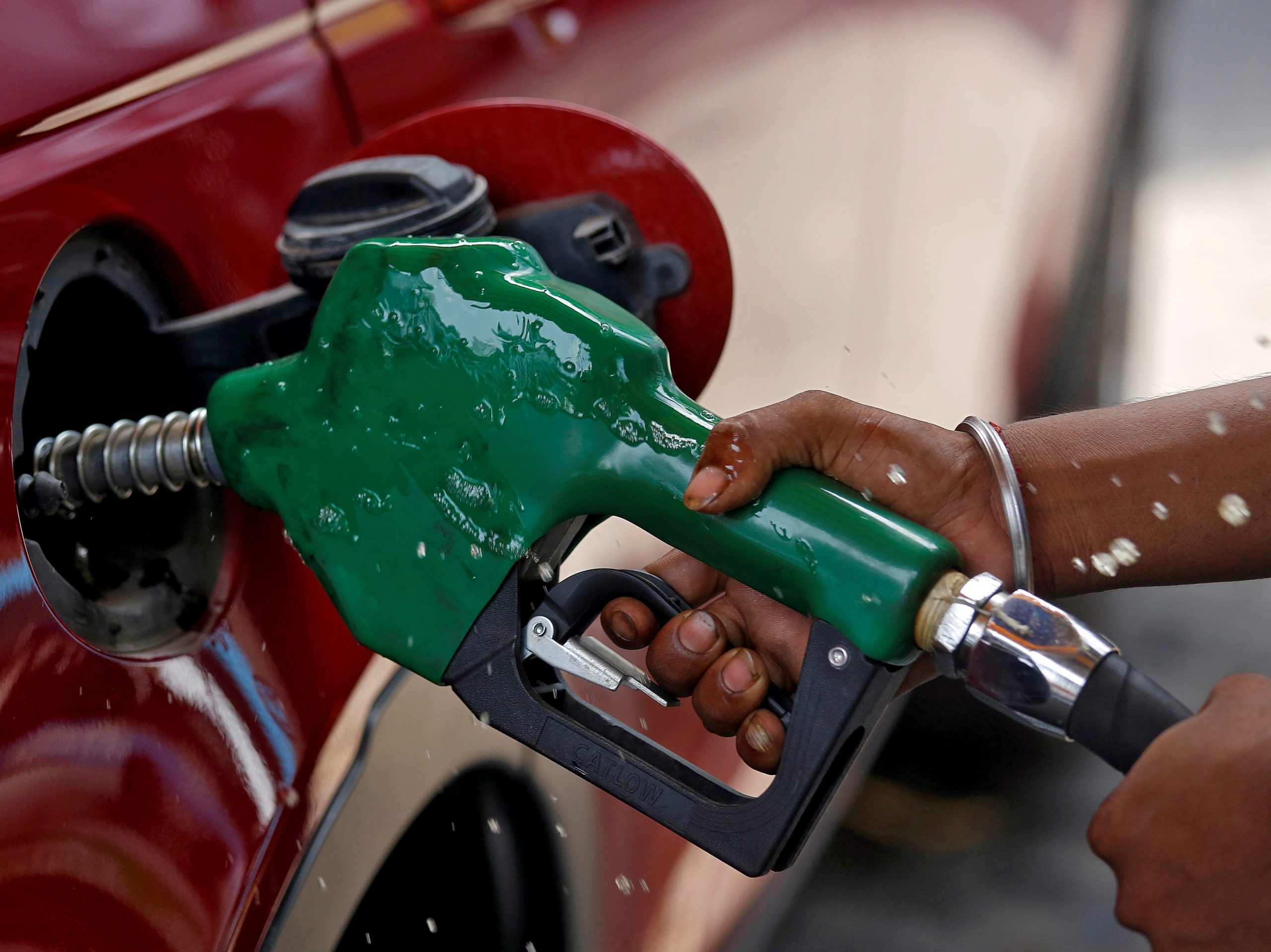 FILE PHOTO: A worker holds a nozzle to pump petrol into a vehicle at a fuel station in Mumbai, India, May 21, 2018.