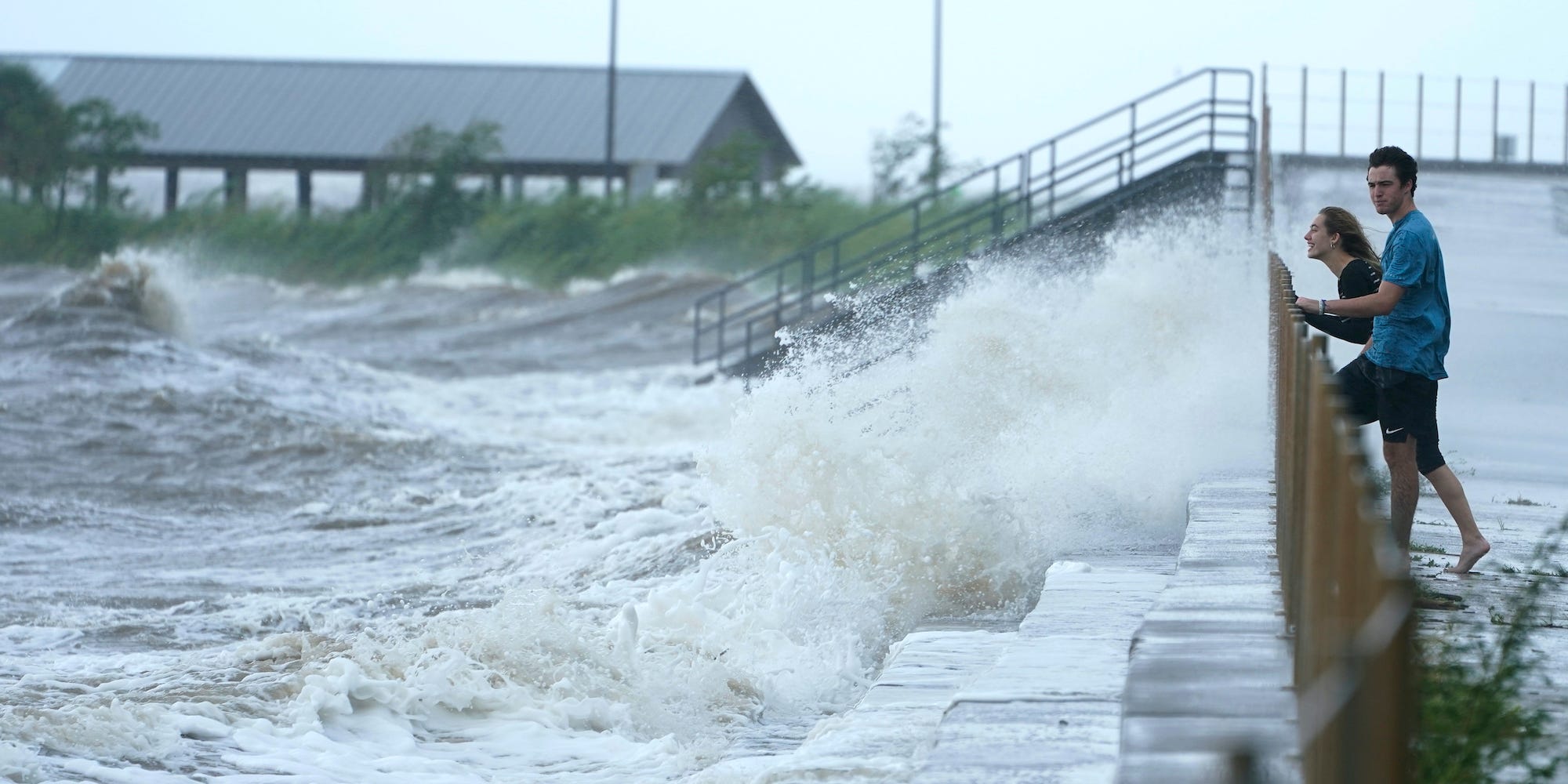 Local residents Portia Potyok, left, and Bradley Darby, watch the wind and waves along a seawall as outer bands of Hurricane Ida arrive Sunday, Aug. 29, 2021, in Bay Saint Louis, Miss