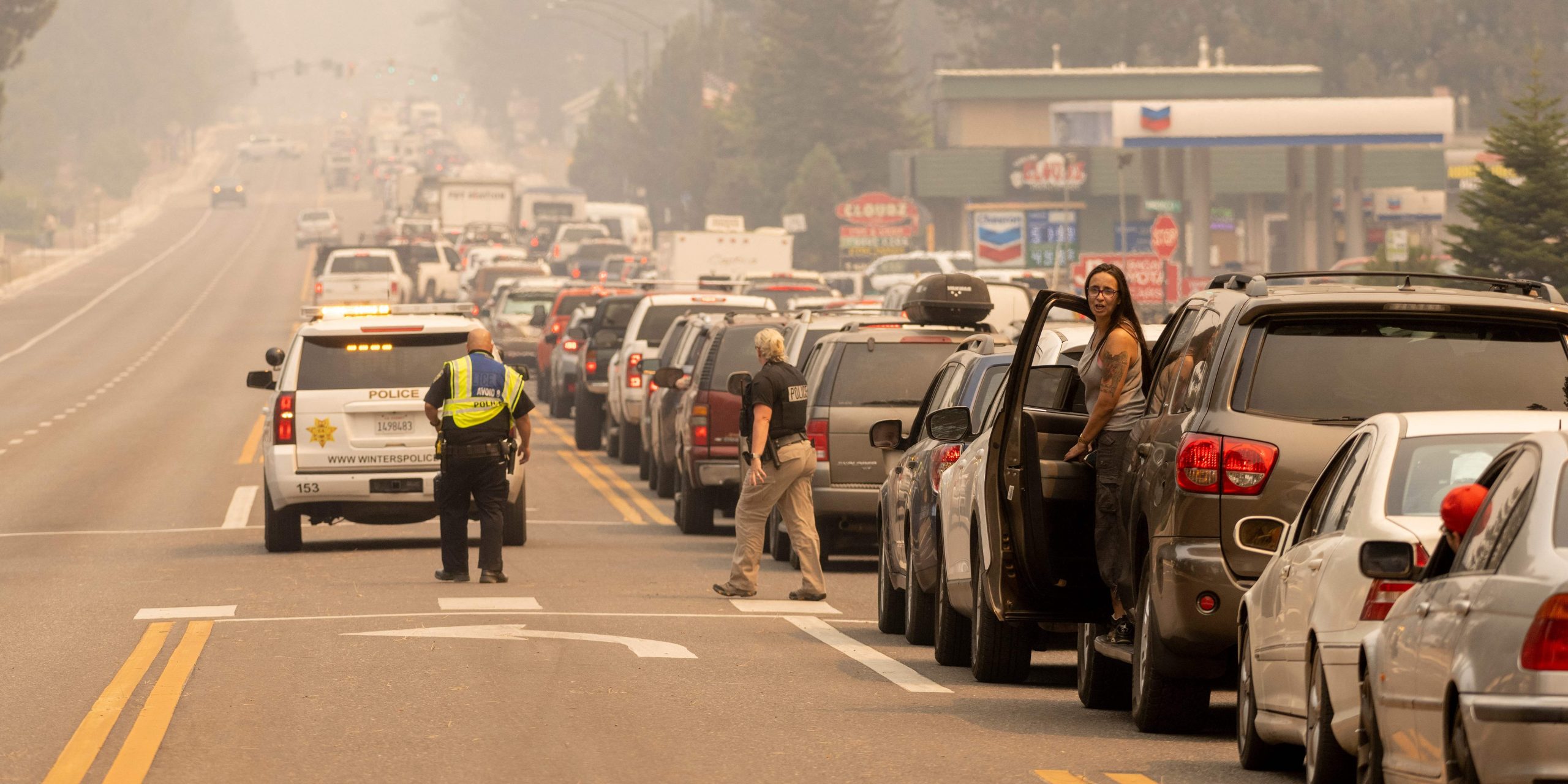 A line of cars attempts to exit South Lake Tahoe as a haze from the Caldor fire sits overhead.