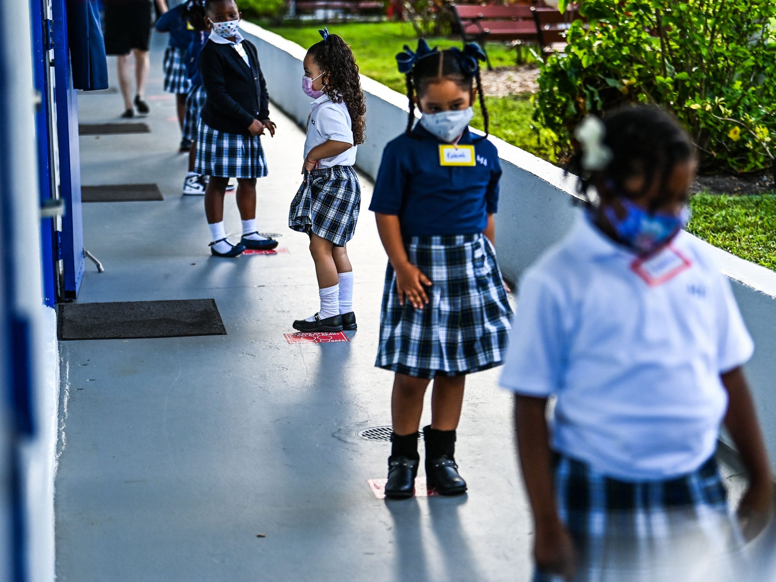 Students wear facemasks and stand in a social distance on their first day of school after summer vacation at the St. Lawrence Catholic School in north of Miami, Florida, on August 18, 2021.