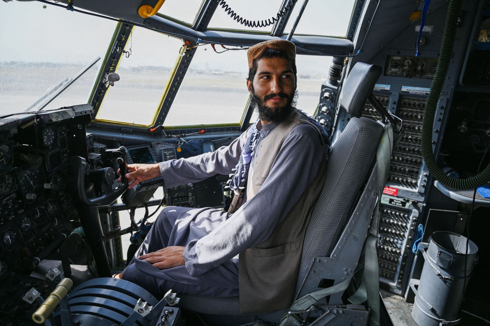 A Taliban fighter smiles as he sits in the cockpit of a jet