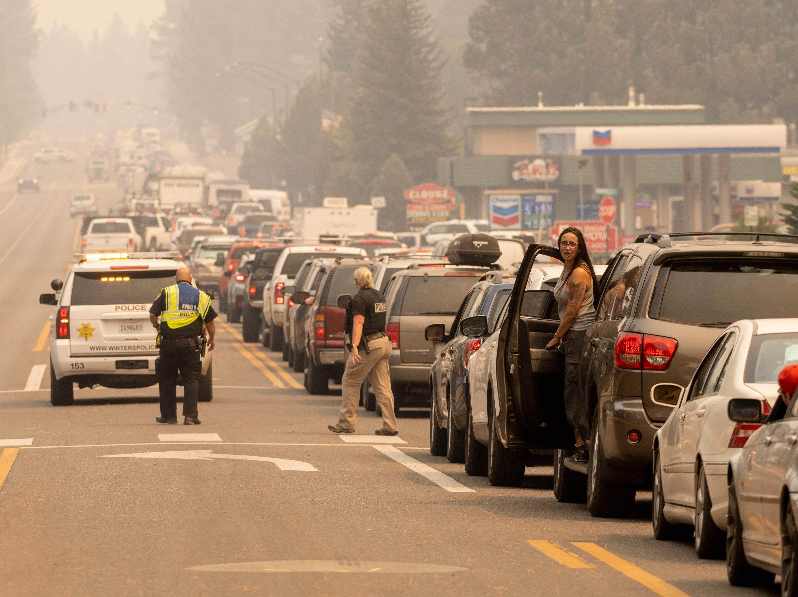 A line of cars attempts to exit South Lake Tahoe as a haze from the Caldor fire sits overhead.