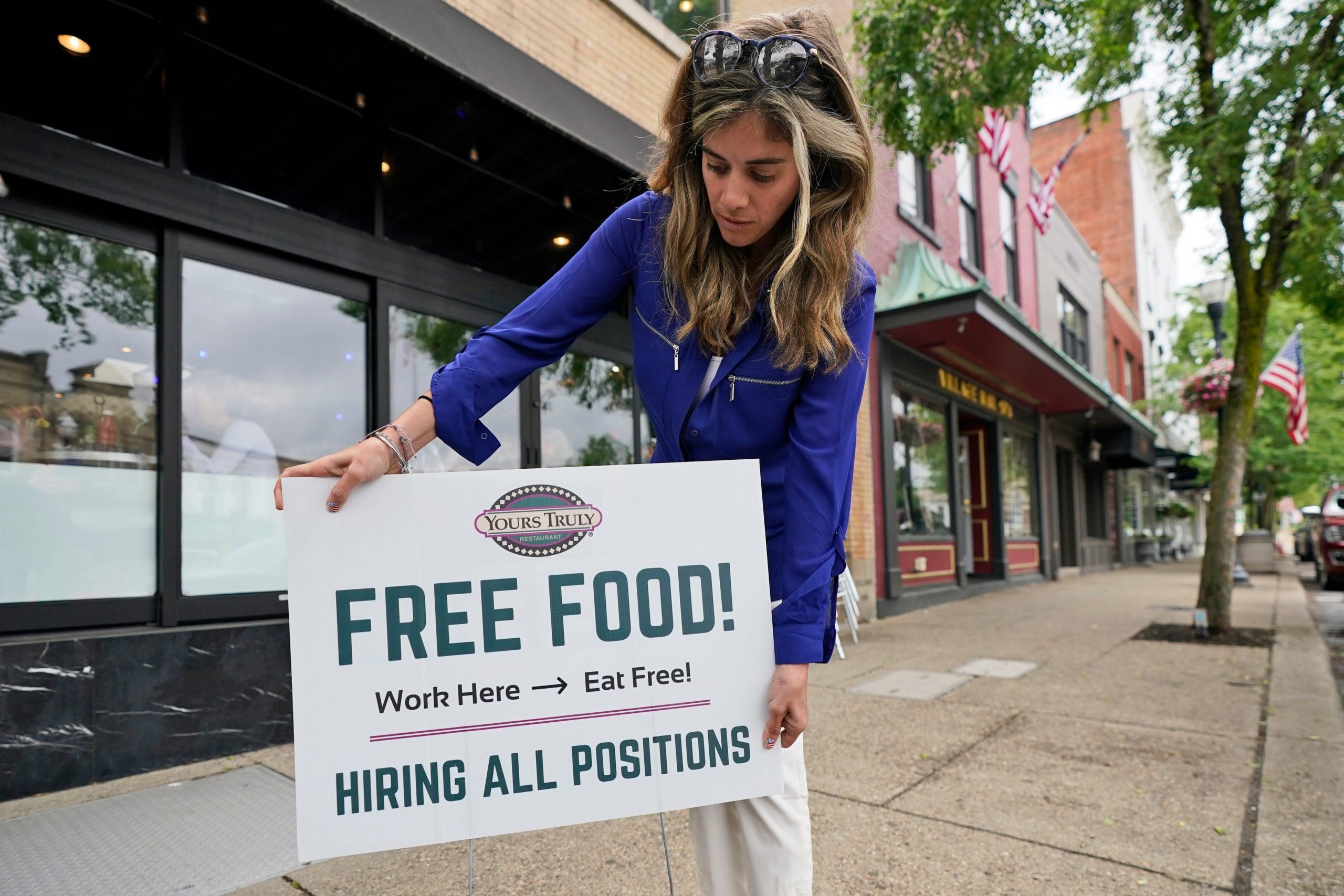 Coleen Piteo, director of marketing at Yours Truly restaurant, puts out a sign that says, "Free Food" and "Hiring all positions" to lure in job applicants.