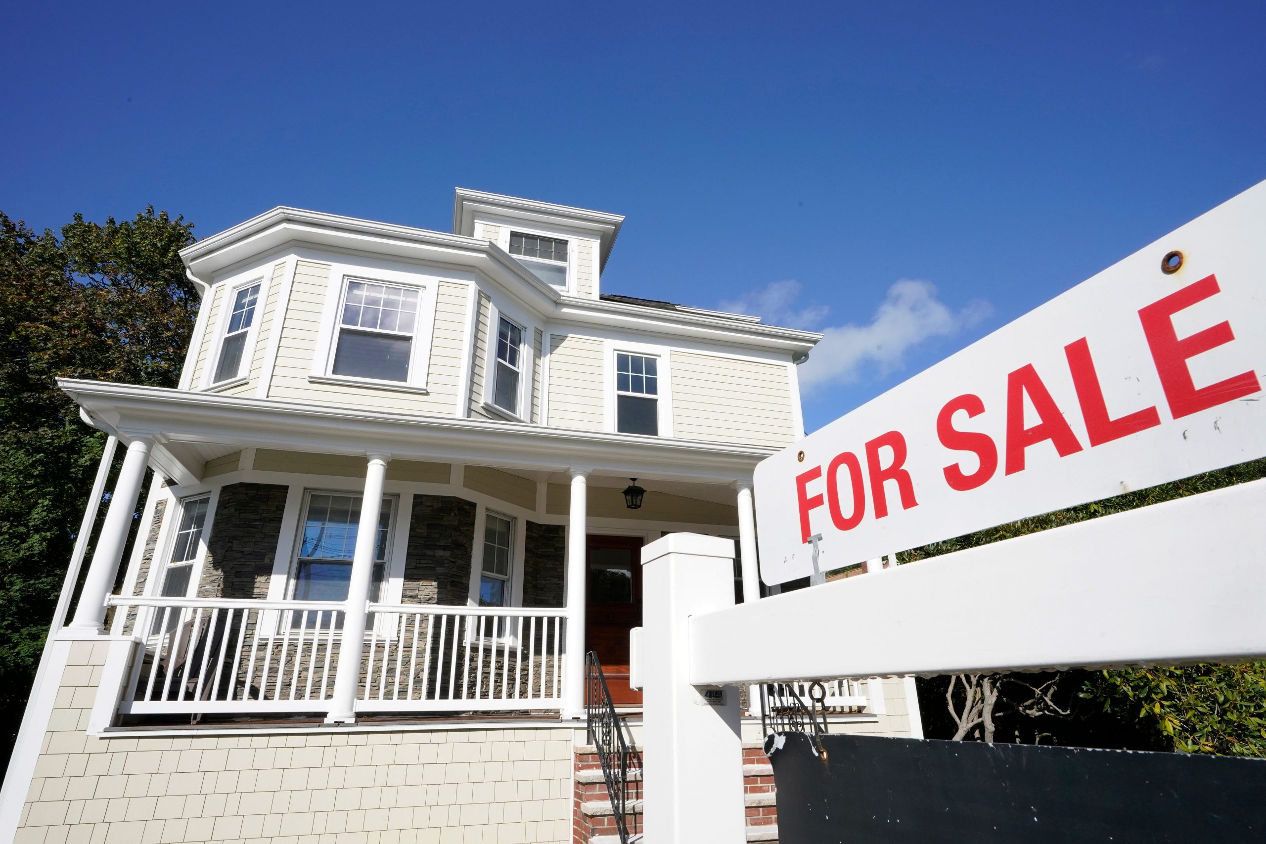 A for sale sign stands in front of a house in Westwood, Mass.