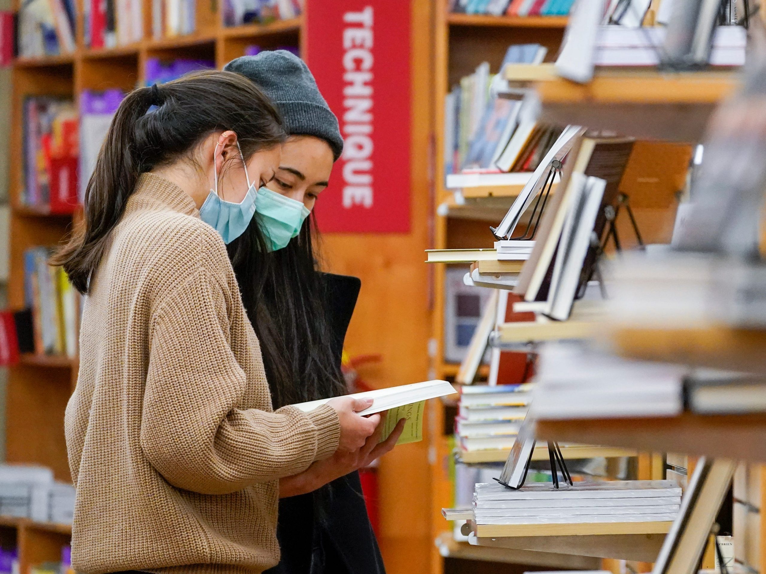 Two women wearing masks browse books at The Strand Bookstore in New York City