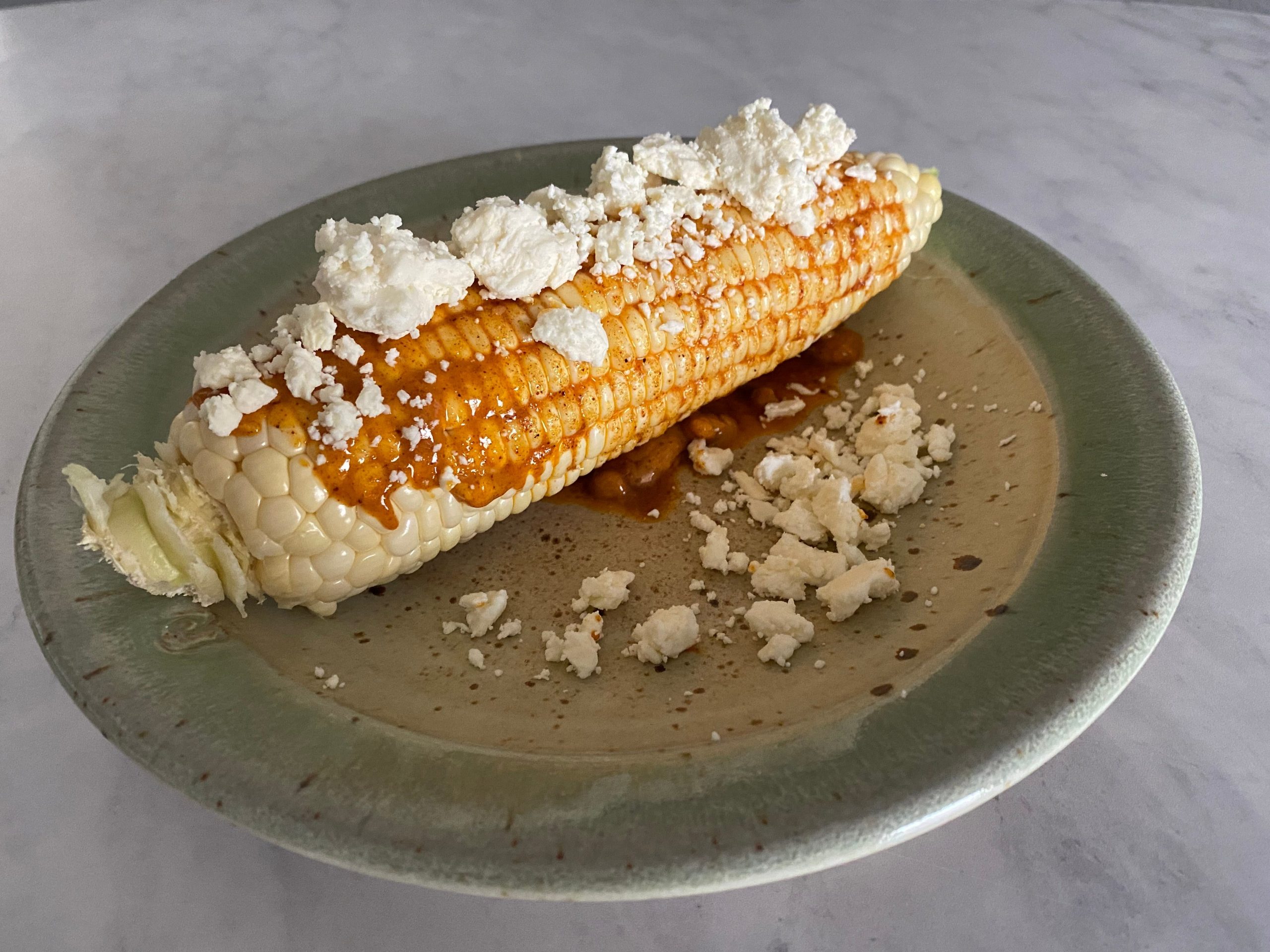 Corn on the cob with crumbled feta.