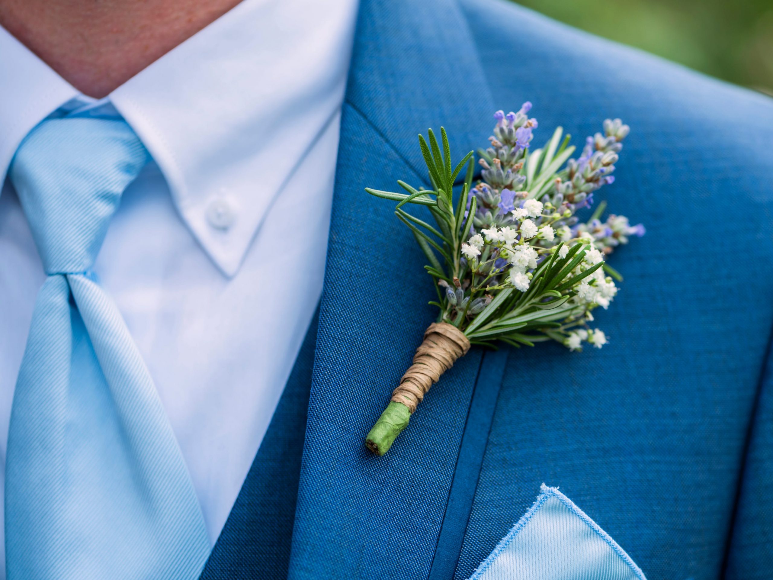 A man in a blue suit with a purple, white, and green boutonniere