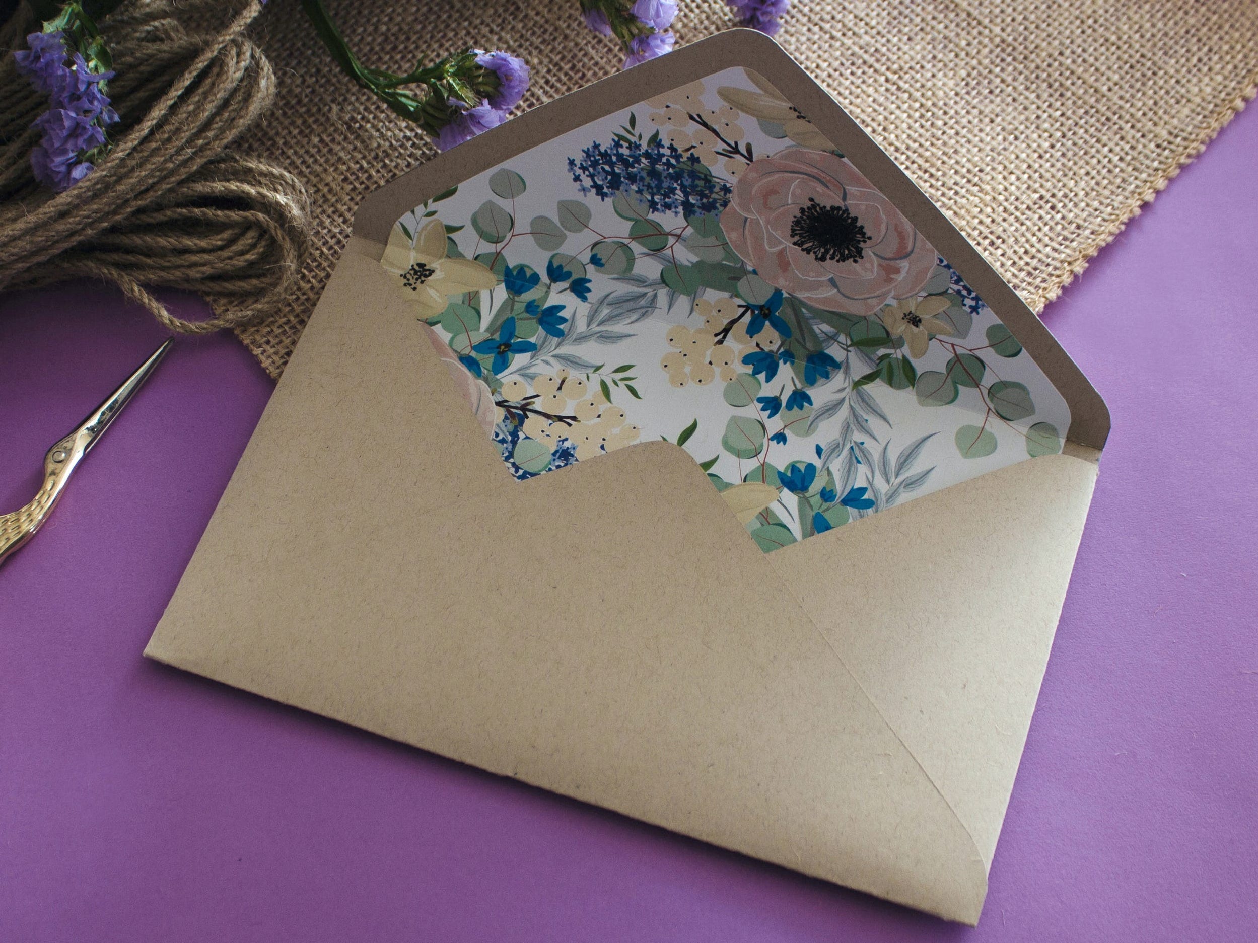 Brown envelop with colorful floral lining on purple table