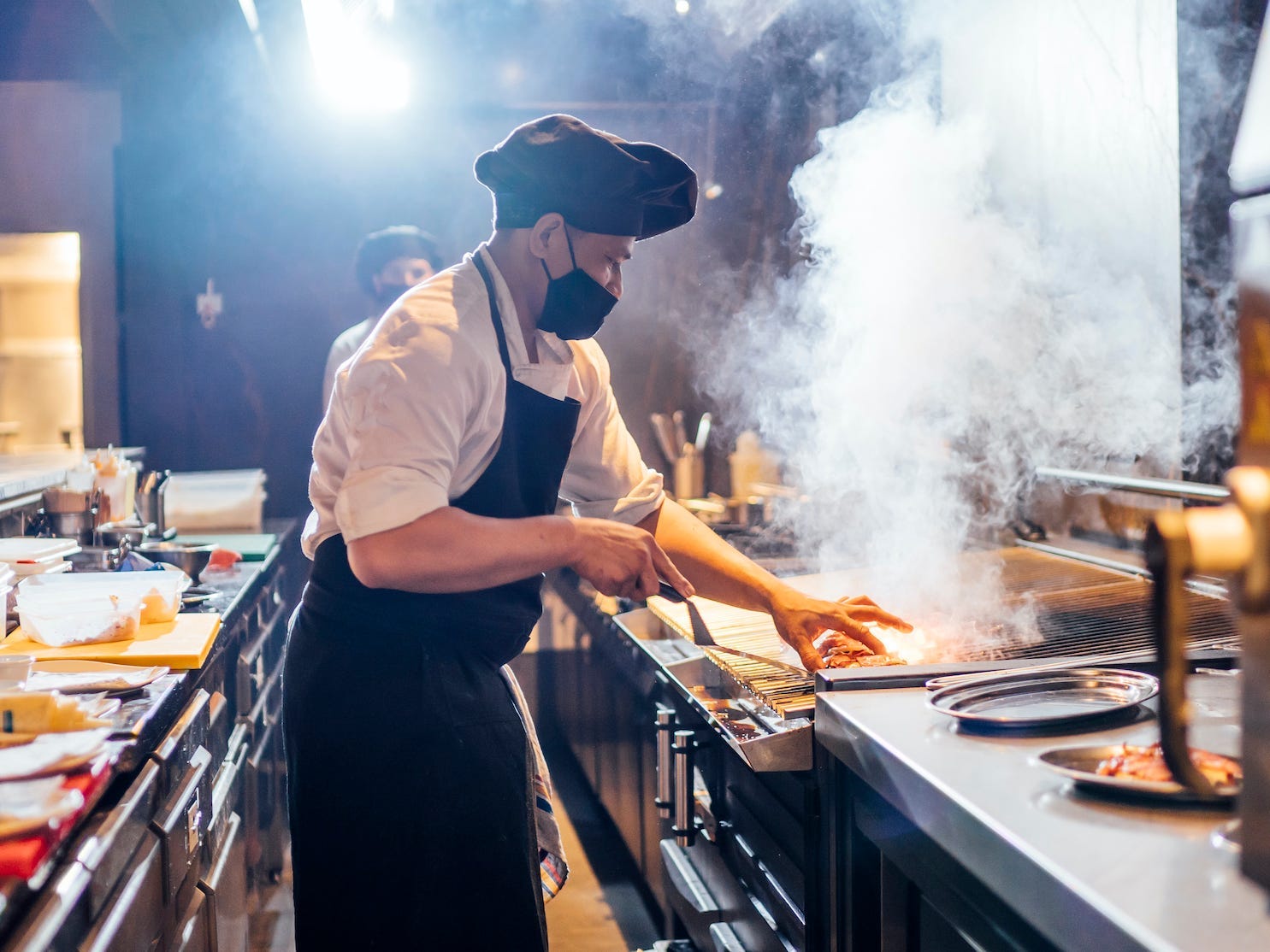 chef cooking in a restaurant kitchen and wearing a mask