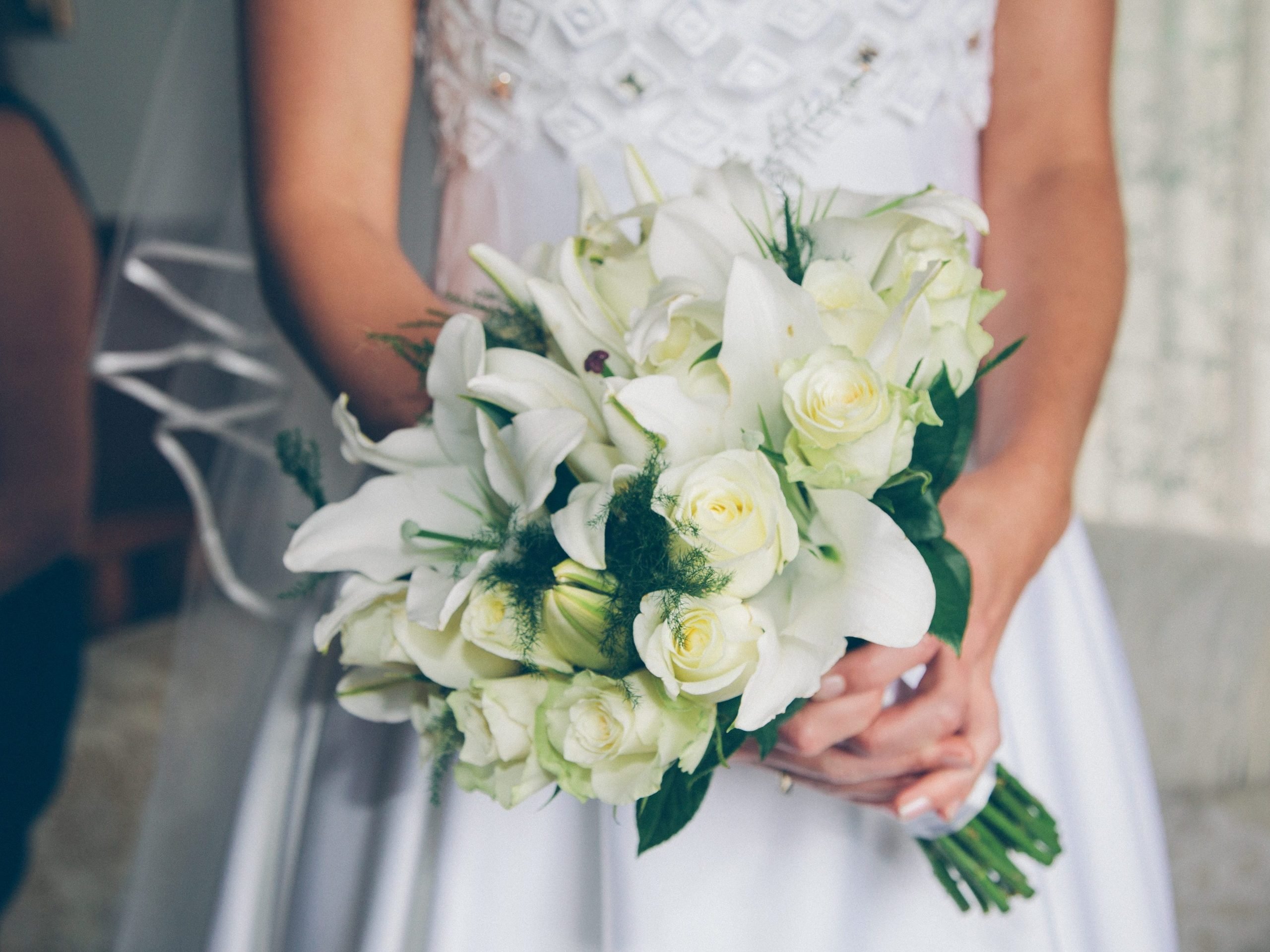 A bride wearing a white dress holds a flower bouquet