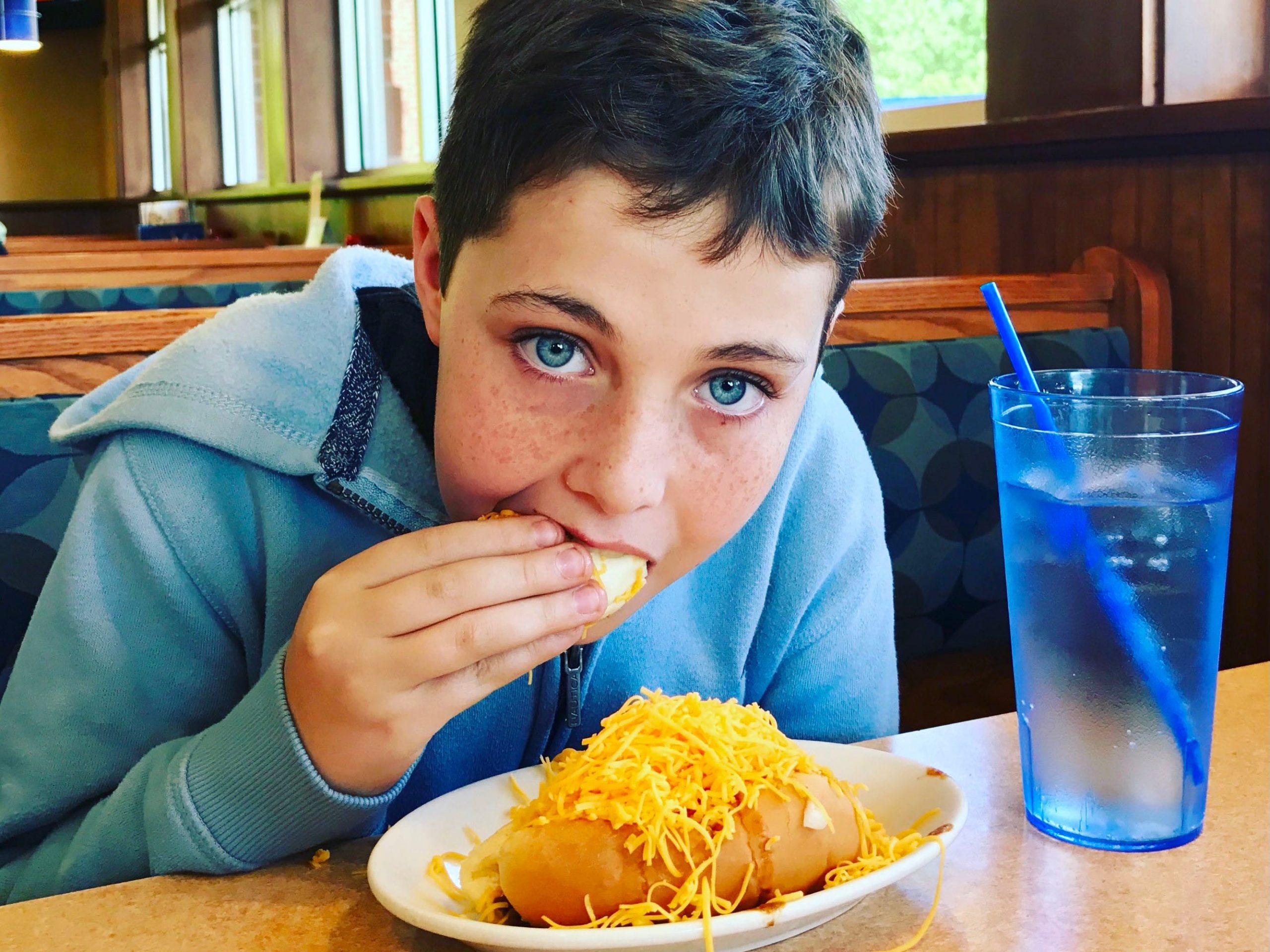 A person eating a dish from Skyline Chili inside