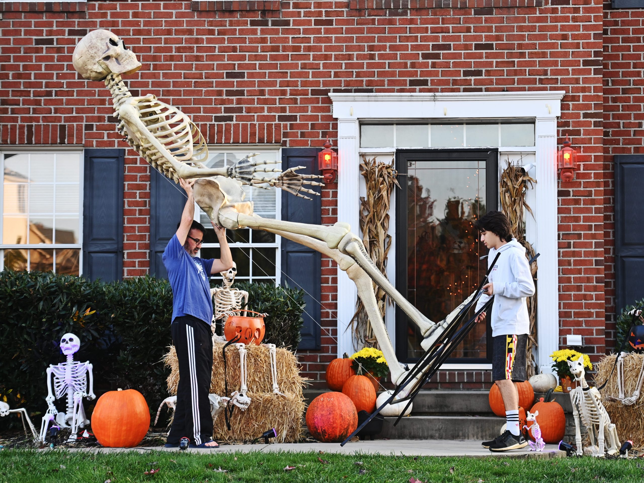 A father and son take their 12-foot-tall Home Depot skeleton into storage after Halloween.