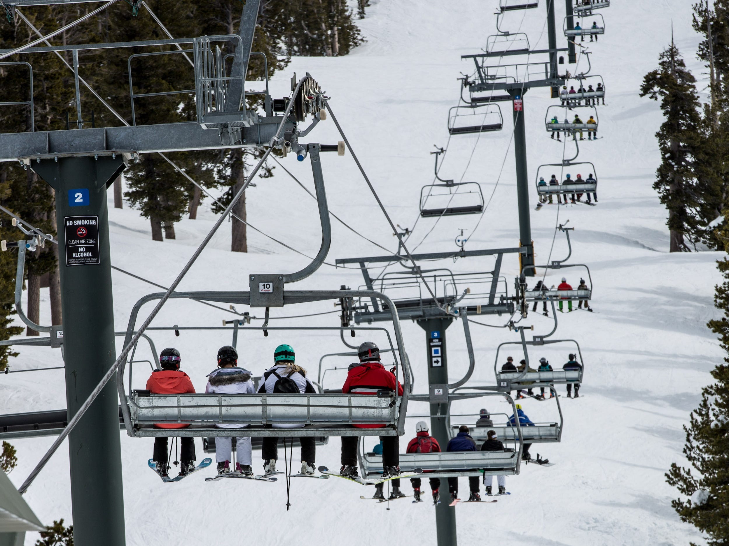 Skiers on chairlift heading up snow-covered mountain in Lake Tahoe