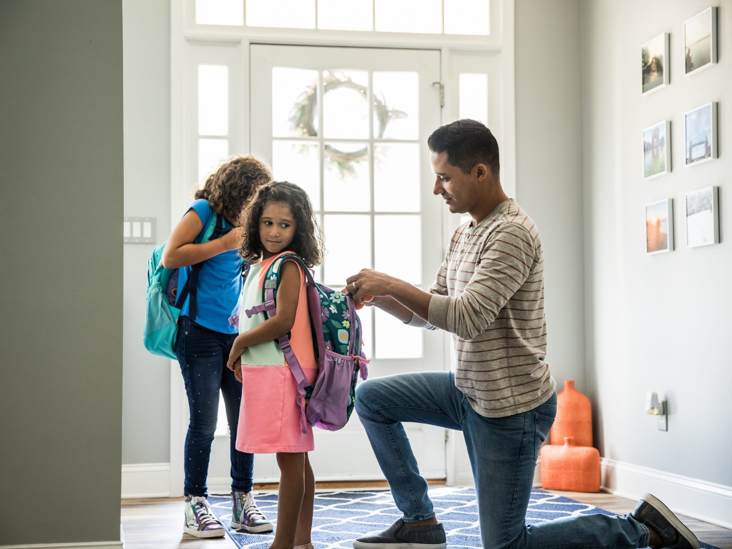 man helping child zip up backpack. back to school