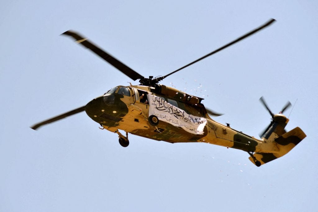 A helicopter displaying a Taliban flag fly above of supporters gathered to celebrate the US withdrawal of all its troops out of Afghanistan, in Kandahar on September 1, 2021.