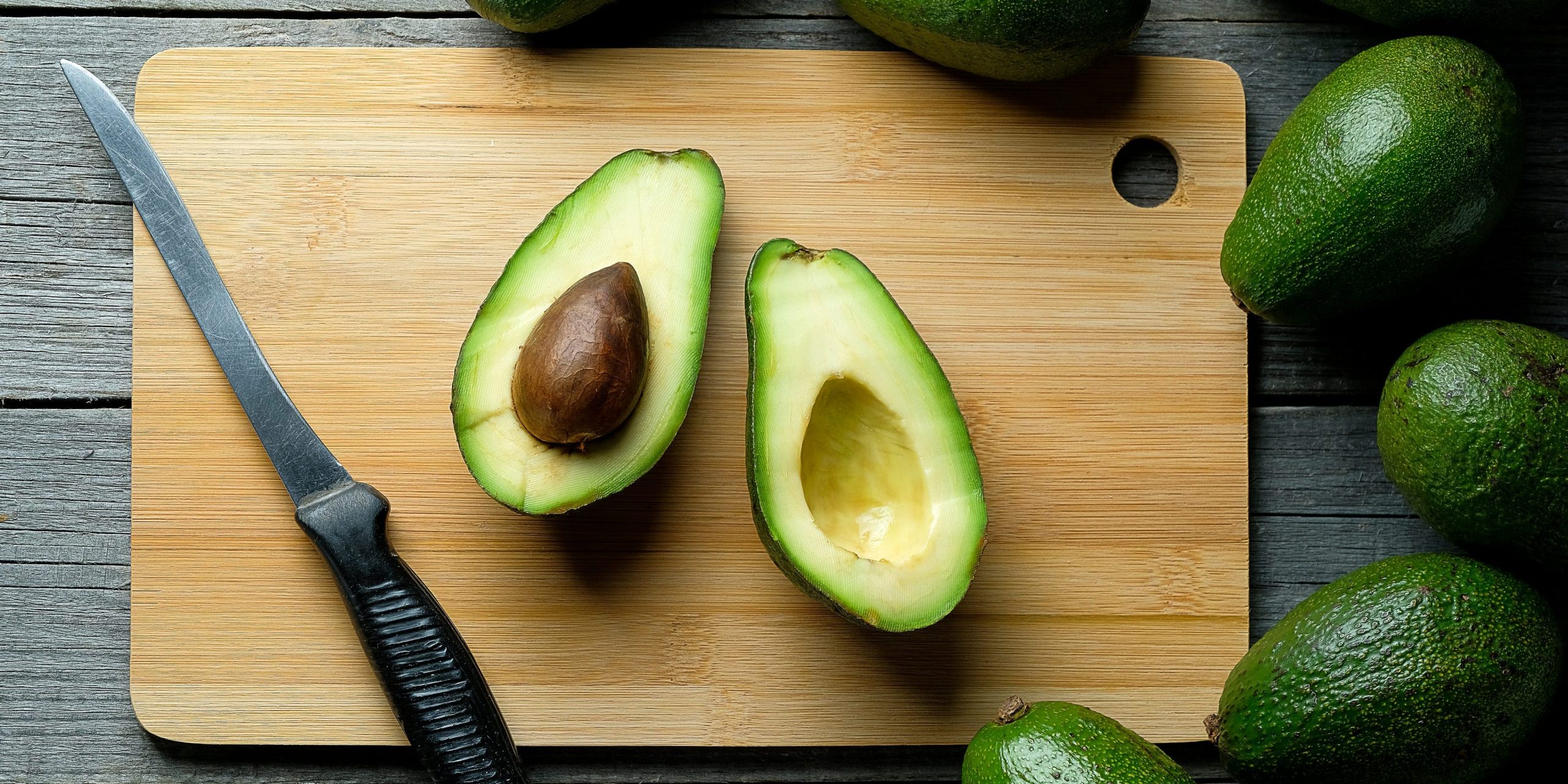 open avocado on wooden cutting board