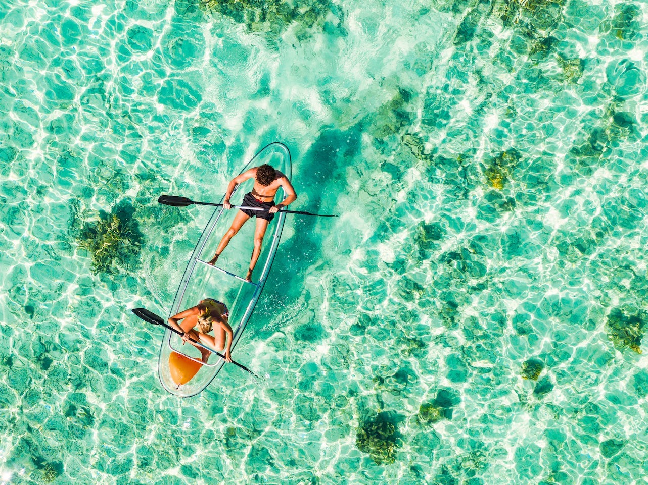 An overhead image of two kayakers in a clear kayak.