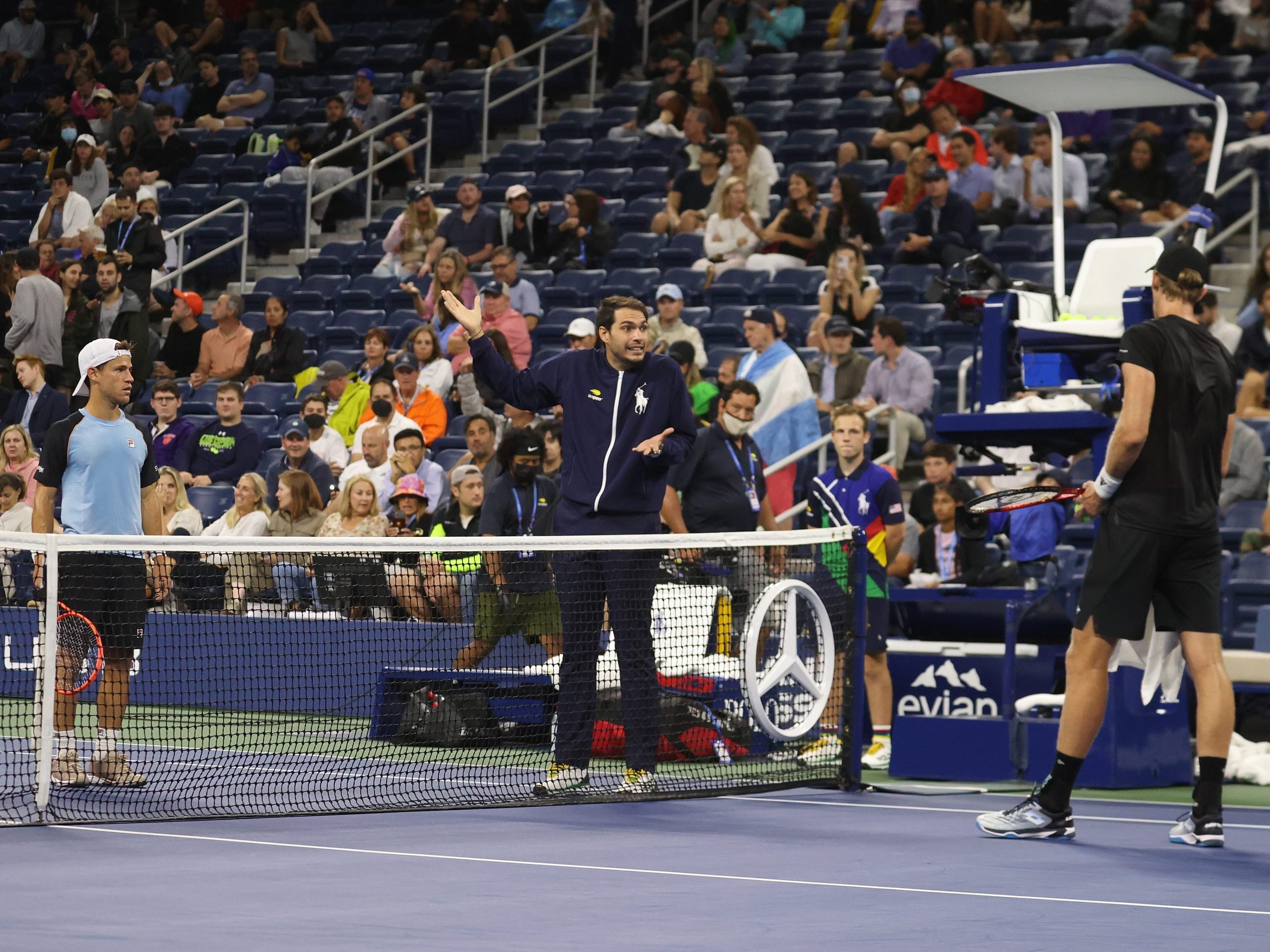 Kevin Anderson of South Africa and Diego Schwartzman of Argentina discuss the wet court with chair umpire during their Men's Singles second round