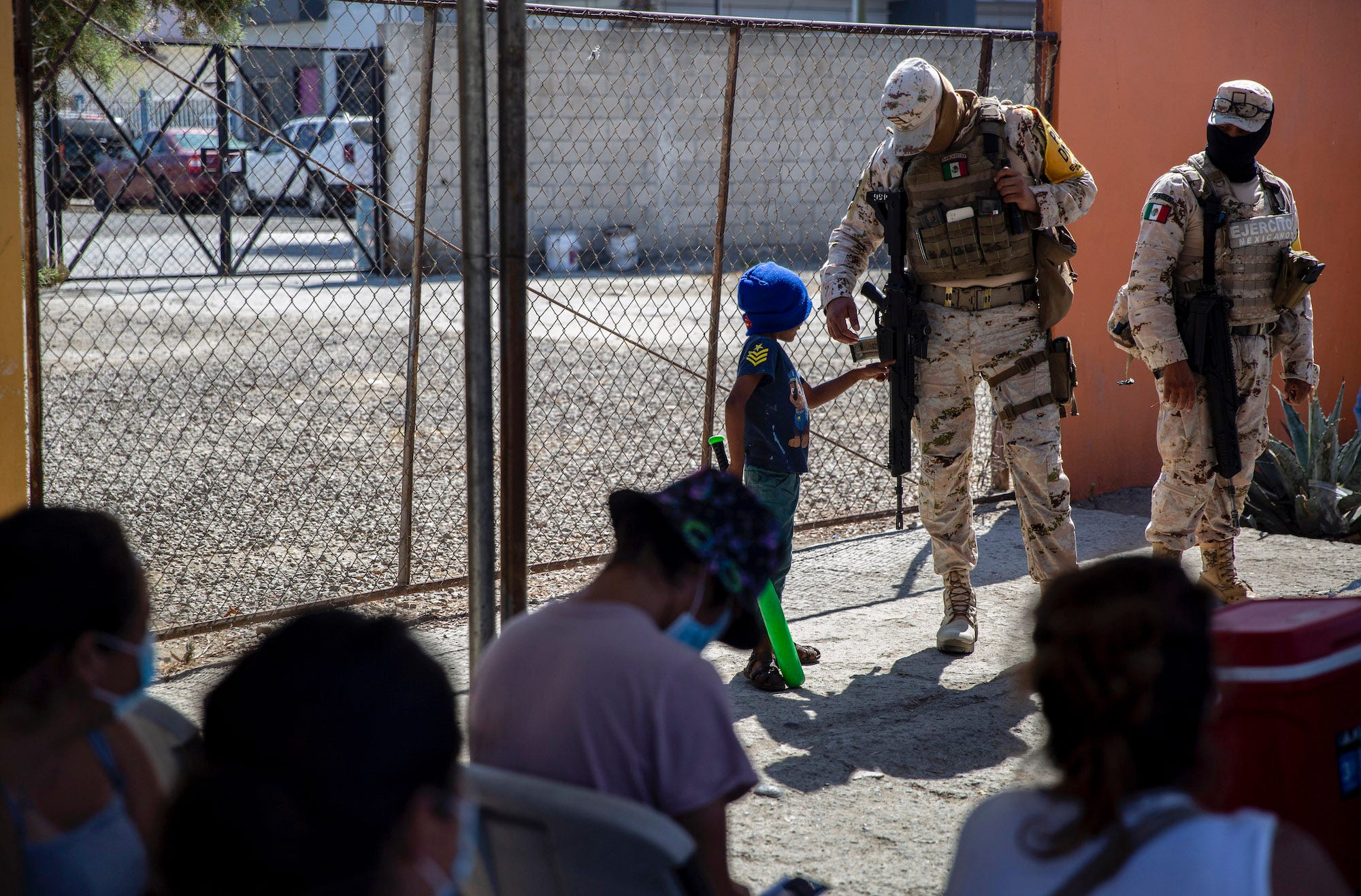 Mexico migrant child looks at soldier gun