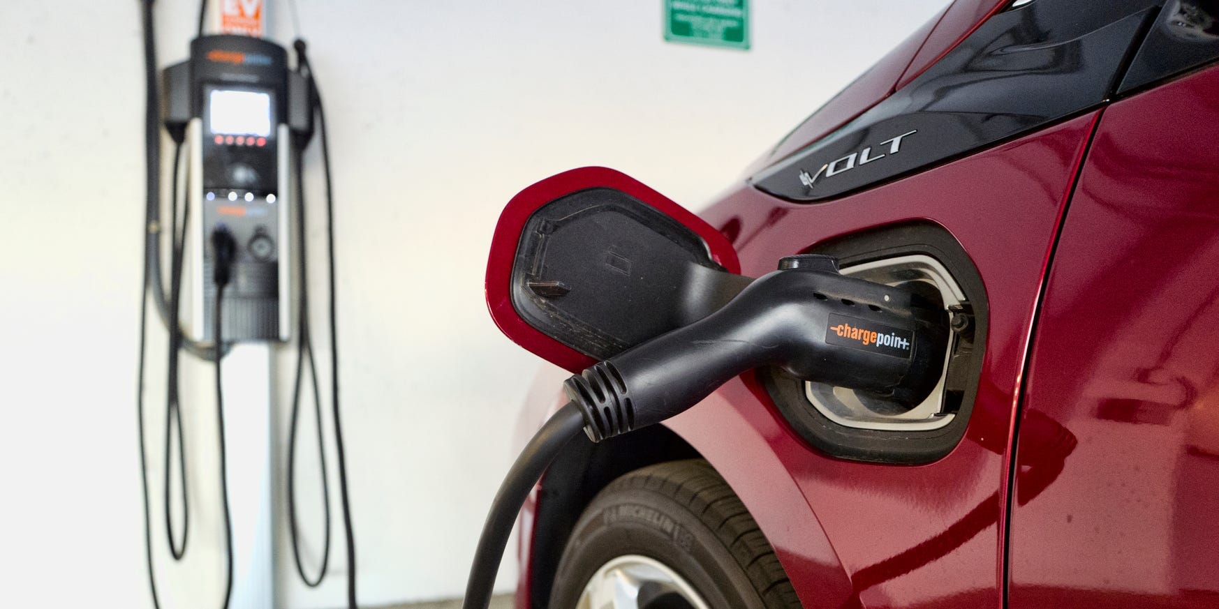 A red Chevrolet Volt hybrid car is charging in a parking garage.