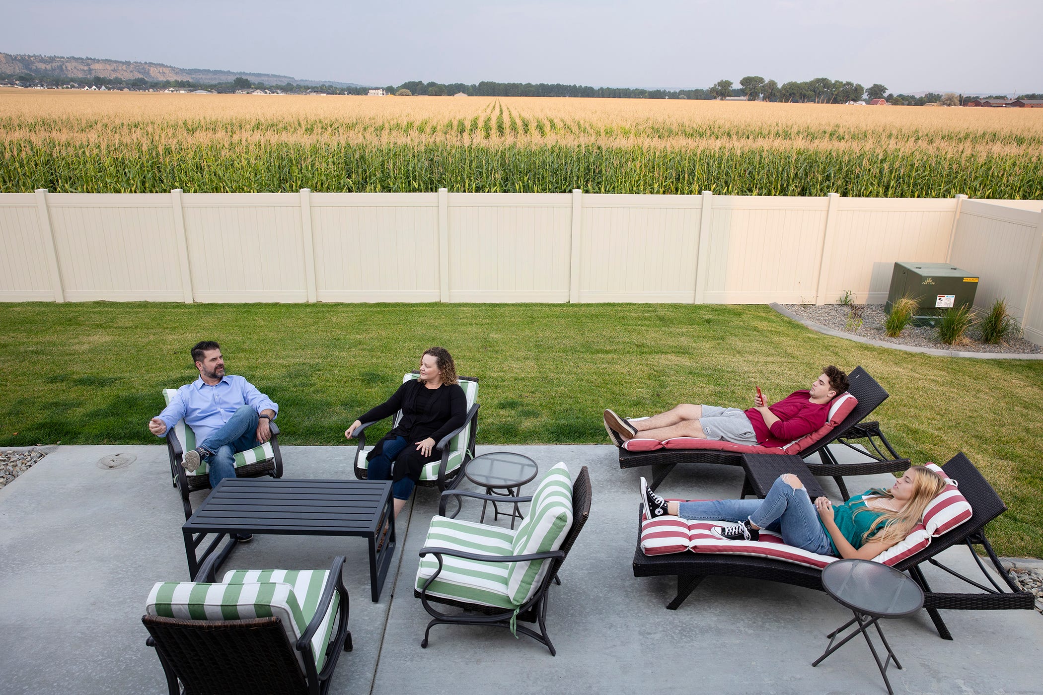 Four members of the Jansezian family lounge on deckchairs on their patio in their back garden.