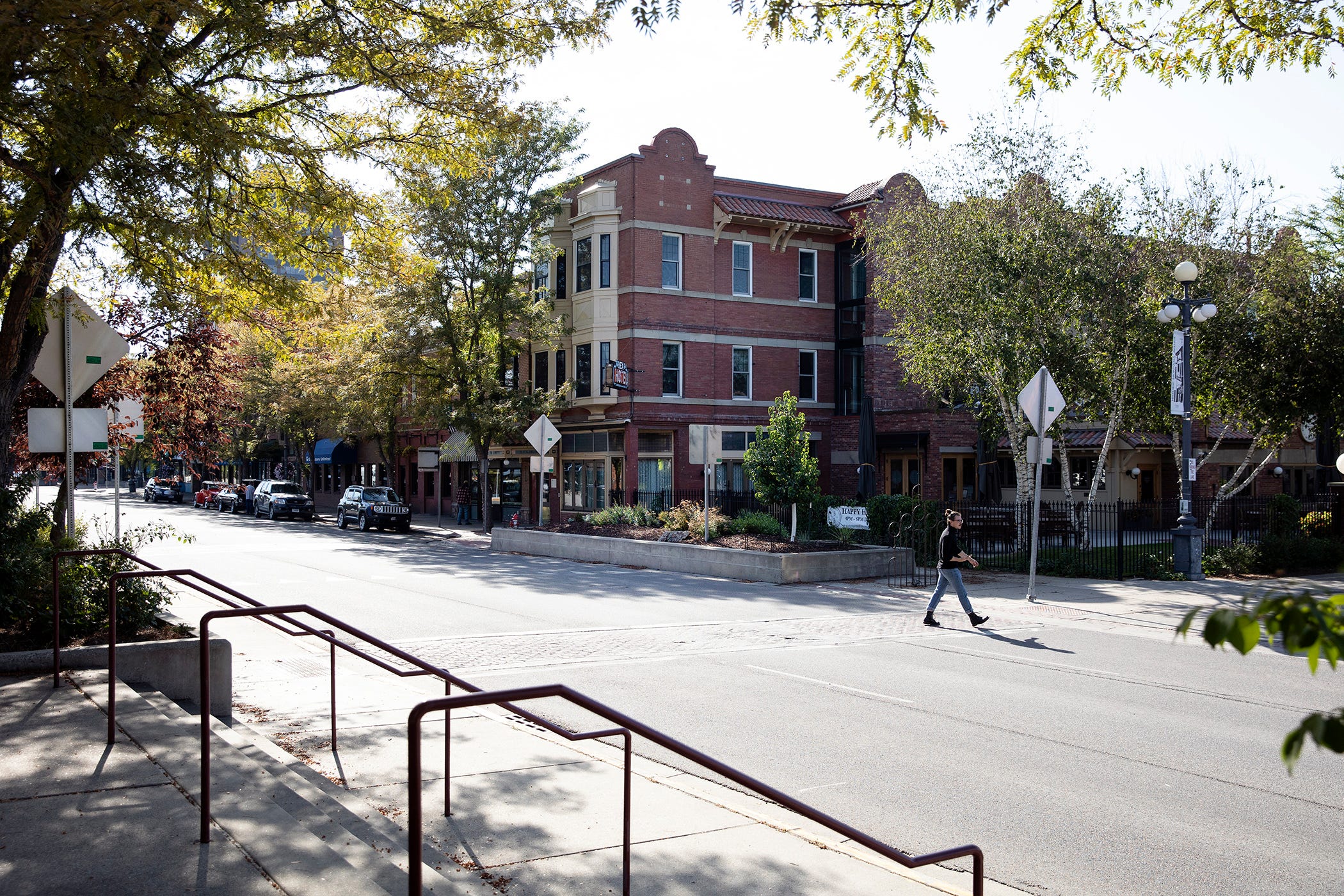 A red-brick building sits at the intersection of two wide streets as the sun beats down onto the tarmac.