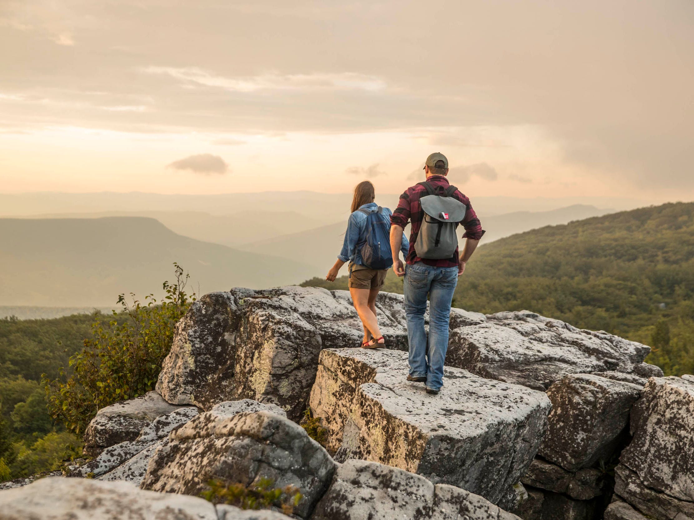 Woman and man hike on rocks at top of mountain in West Virginia