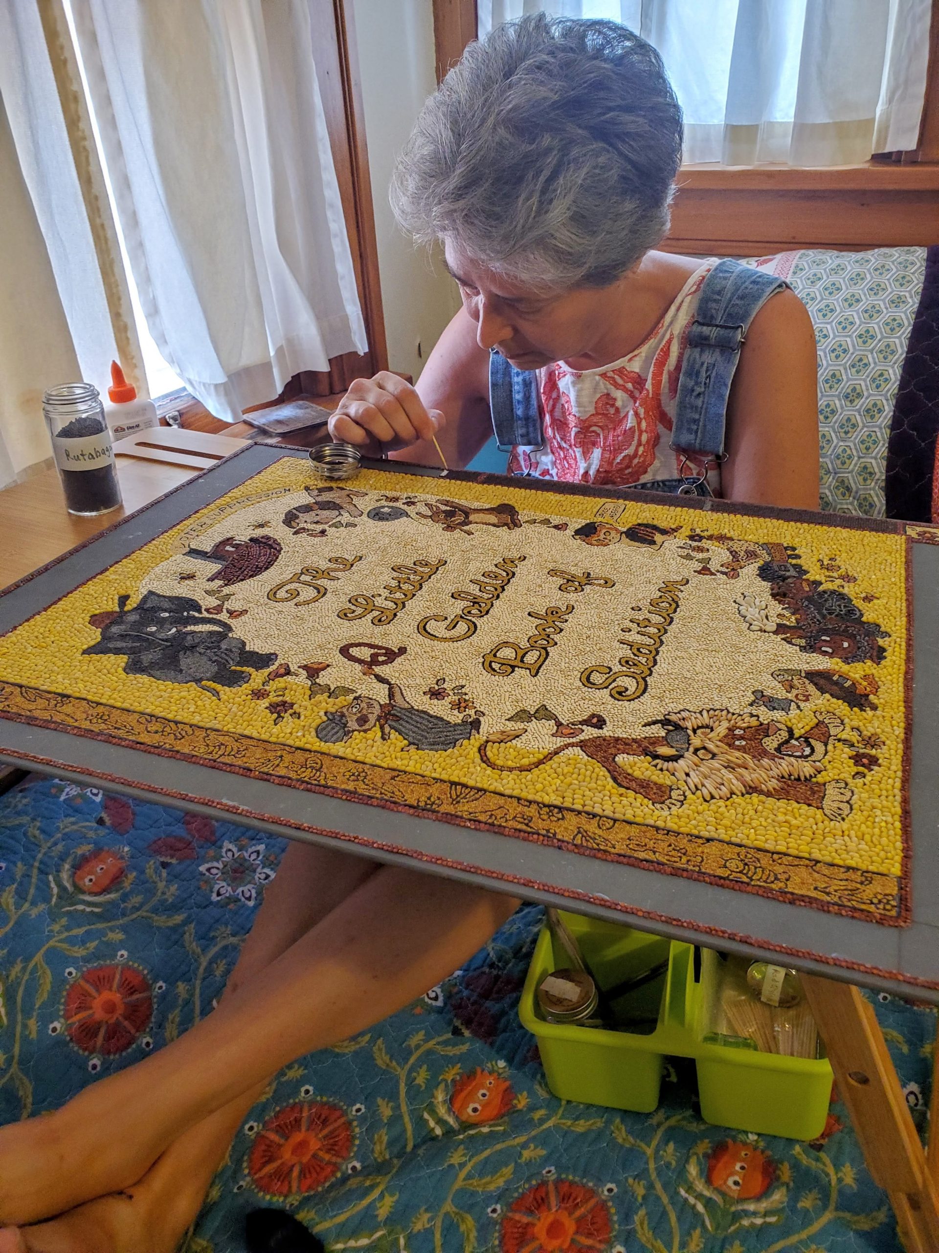 A woman holds a canvas on her lap as she sets seeds.