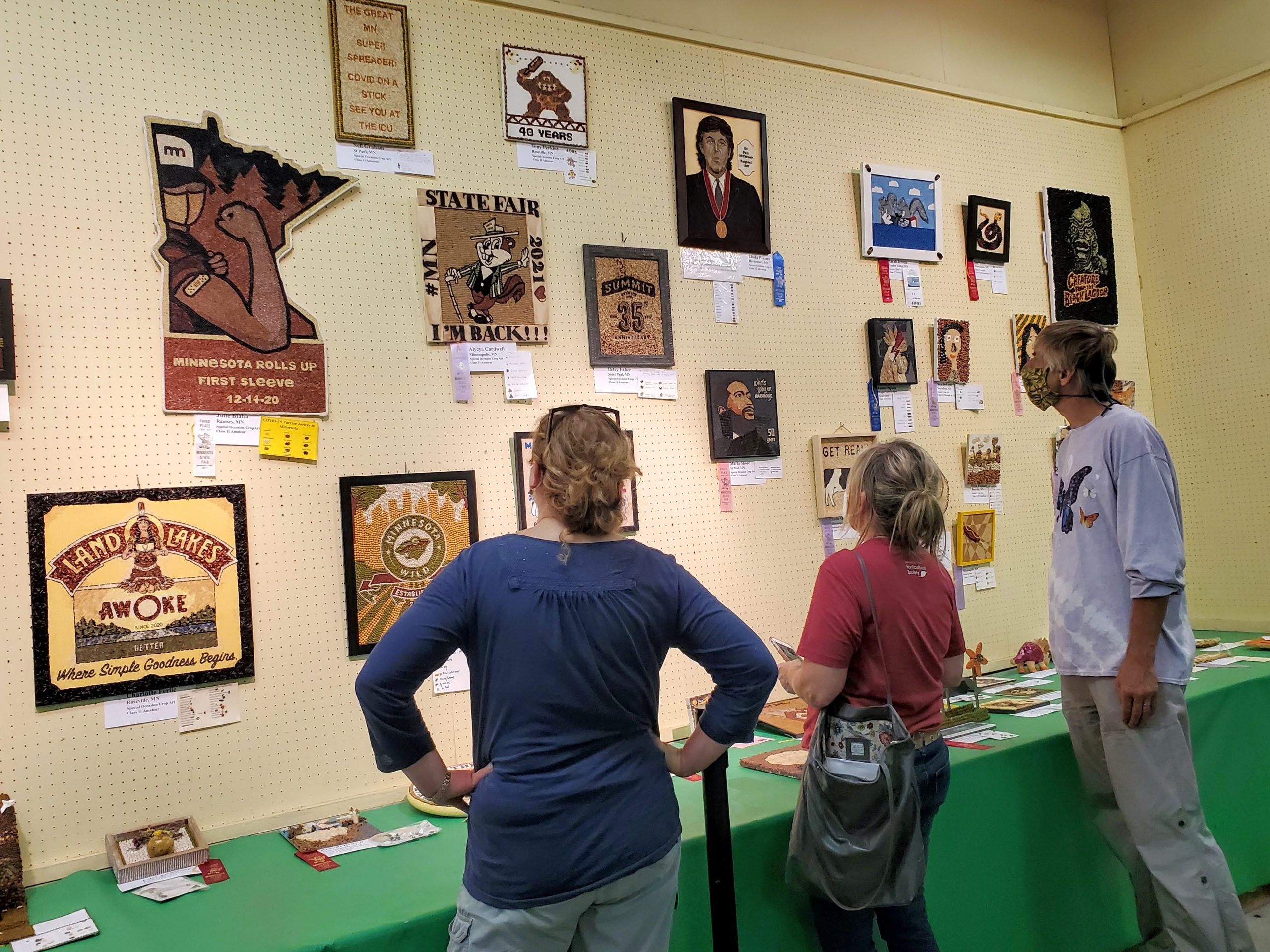 Three people look at art on the wall.