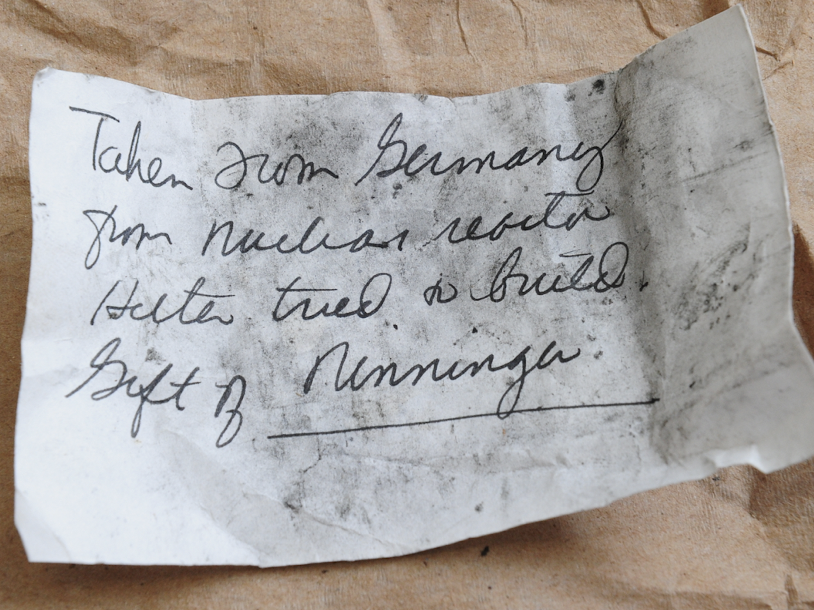 A note on a small piece of white paper handwritten in black ink reads: "Taken from Germany from nuclear reactor Hitler tried to build gift of Ninninger."