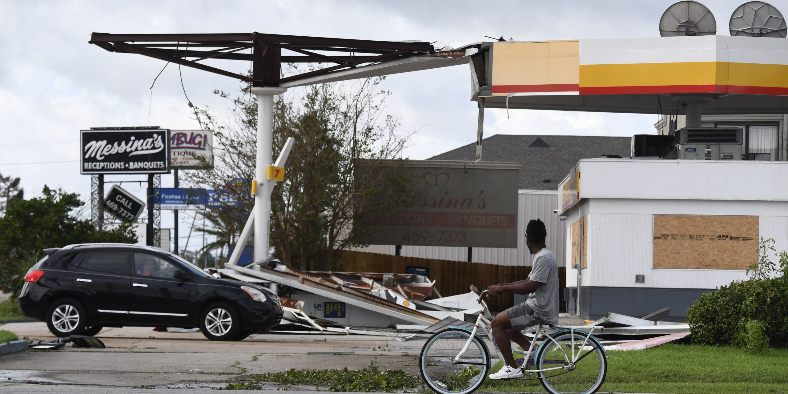 A person on a bicycle passes a damaged Shell station in Kenner, Louisiana, on August 30, 2021 after Hurricane Ida made landfall. - Powerful Hurricane Ida battered the southern US state of Louisiana, leaving at least one dead and knocking out power for more than a million people, including the whole of New Orleans.