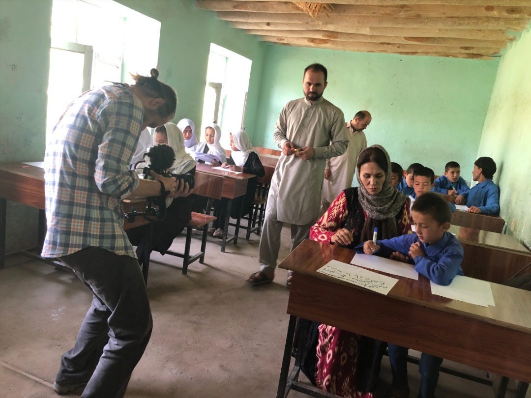 Nigel Walker holding a camera, filming a group of students at desks.