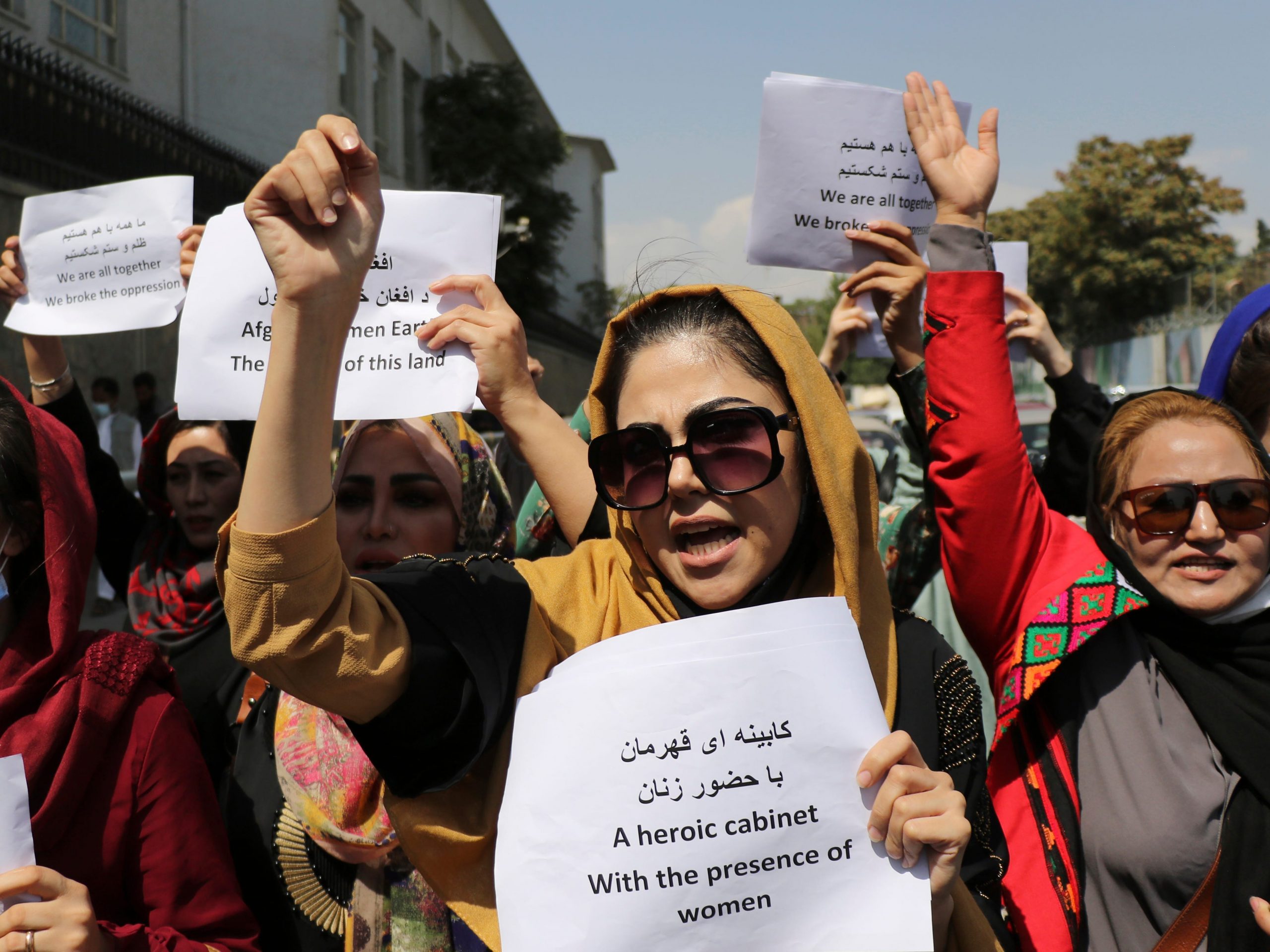 A group of Afghan women holding up signs and their fists in protest in Afghanistan.