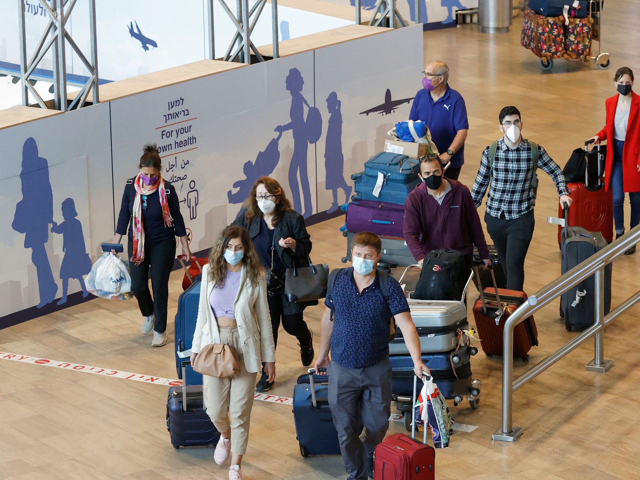 Israelis and vaccinated tourists wearing masks for COVID-19 protection arrive to Israel's Ben Gurion Airport near Tel Aviv on May 23, 2021, after a partial re-opening of the border to inoculated tourists from 14 countries.
