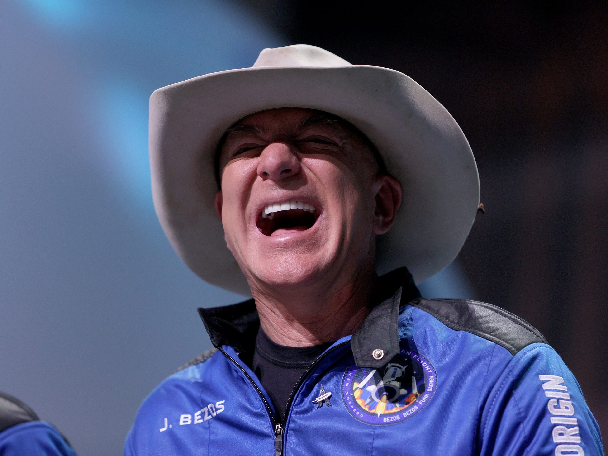 Jeff Bezos laughs wearing a cowboy hat