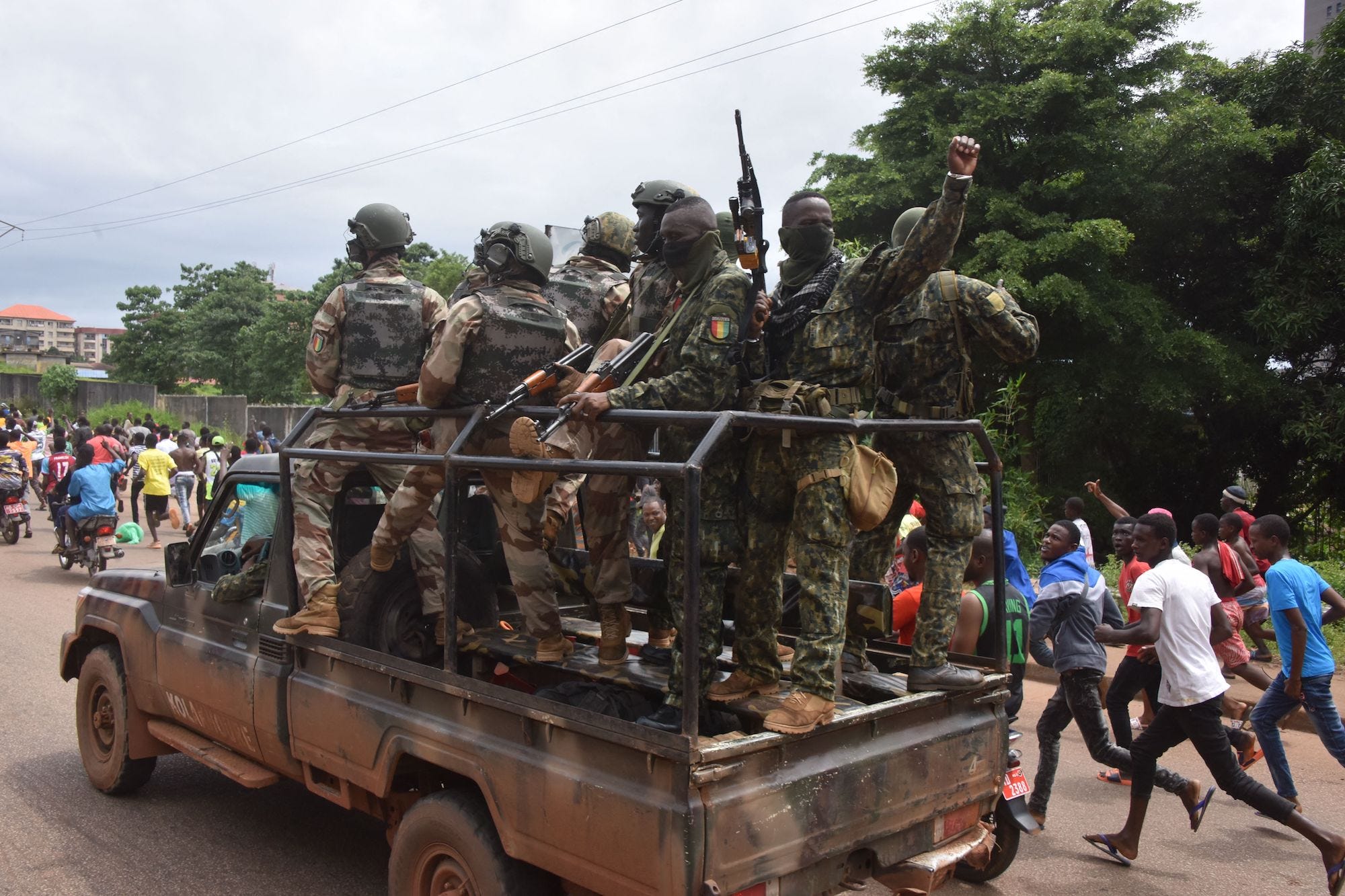 People celebrate in the streets with members of Guinea's armed forces after the arrest of Guinea's president, Alpha Conde, in a coup d'etat in Conakry, September 5, 2021. - Guinean special forces seized power in a coup on September 5, arresting the president and imposing an indefinite curfew in the poor west African country. "We have decided, after having taken the president, to dissolve the constitution," said a uniformed officer flanked by soldiers toting assault rifles