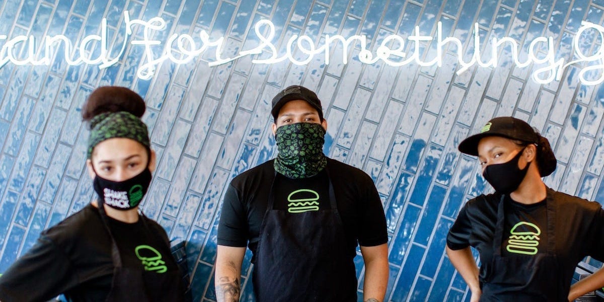Shake Shack workers wearing masks and standing in front of a blue background