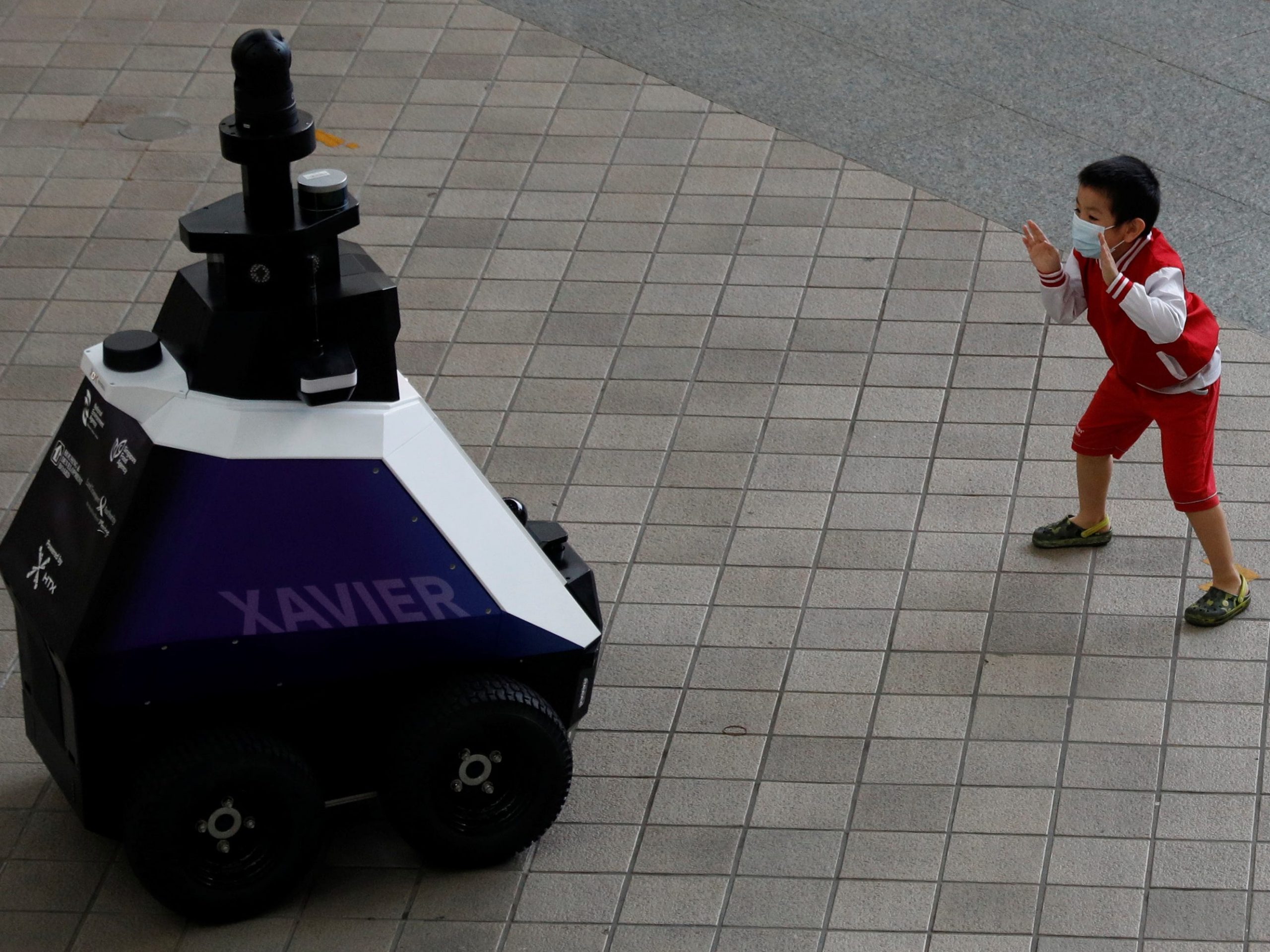 A child poses in front of autonomous robot Xavier, as it patrols a Singapore neighbourhood mall to detect "undesirable social behaviours."