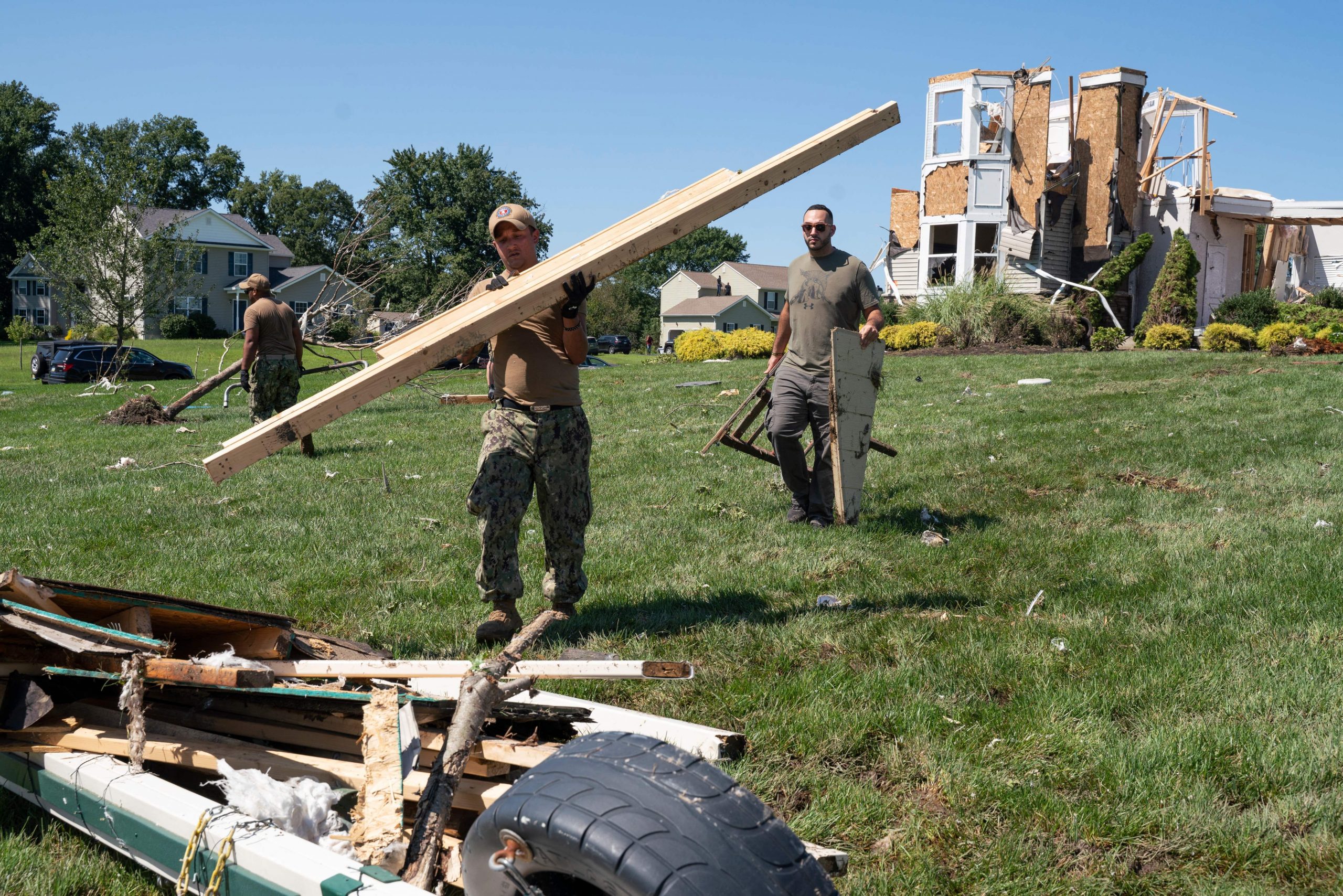 A group of Navy recruiters help clear debris from a house destroyed by a tornado in Mullica Hill, New Jersey after flash floods caused by Ida killed at least 14 people.